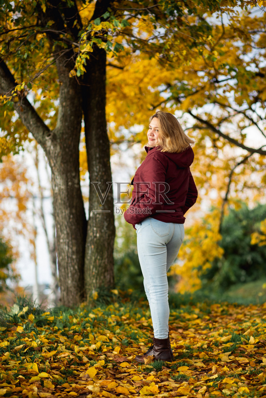 顽皮的年轻女子在秋天的公园里享受秋天的黄叶。人，感情，季节性约会的概念照片摄影图片