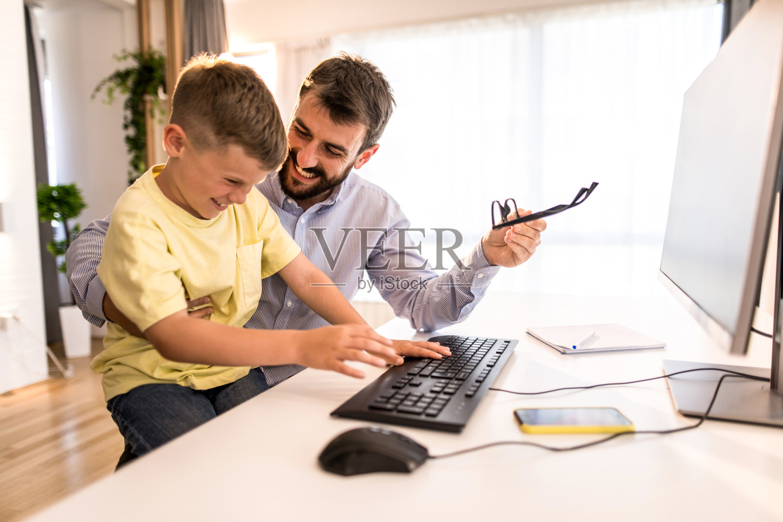 快乐的父子在家里一起工作。照片摄影图片