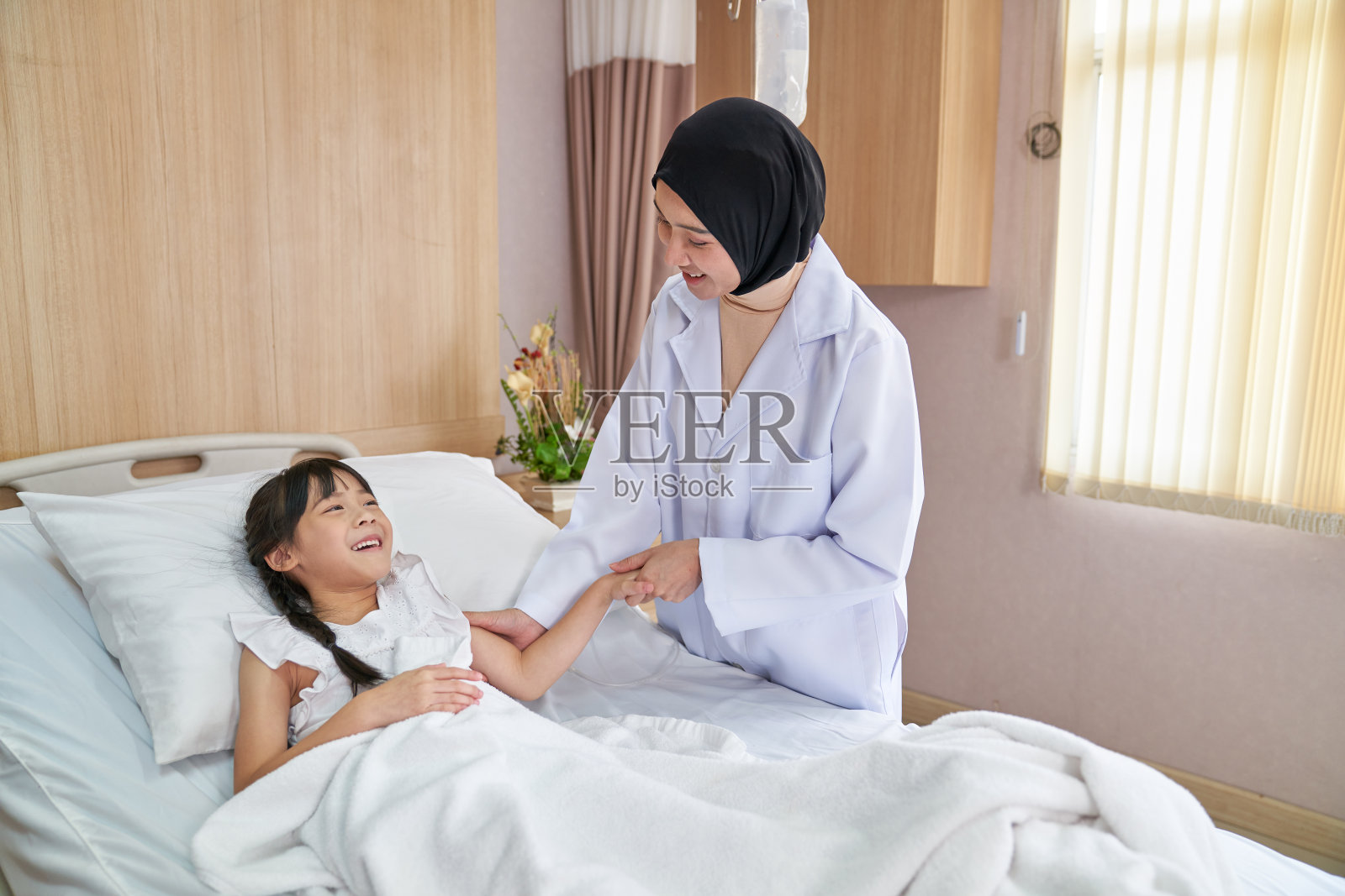 微笑伊斯兰医生治疗可爱快乐的女孩病人在医院b照片摄影图片