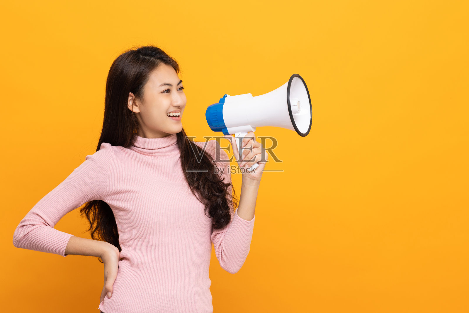 用扩音器大声喊出来。年轻美丽的亚洲女人宣布与一个声音的产品促销和广告打折的价格。购物和时尚概念。照片摄影图片