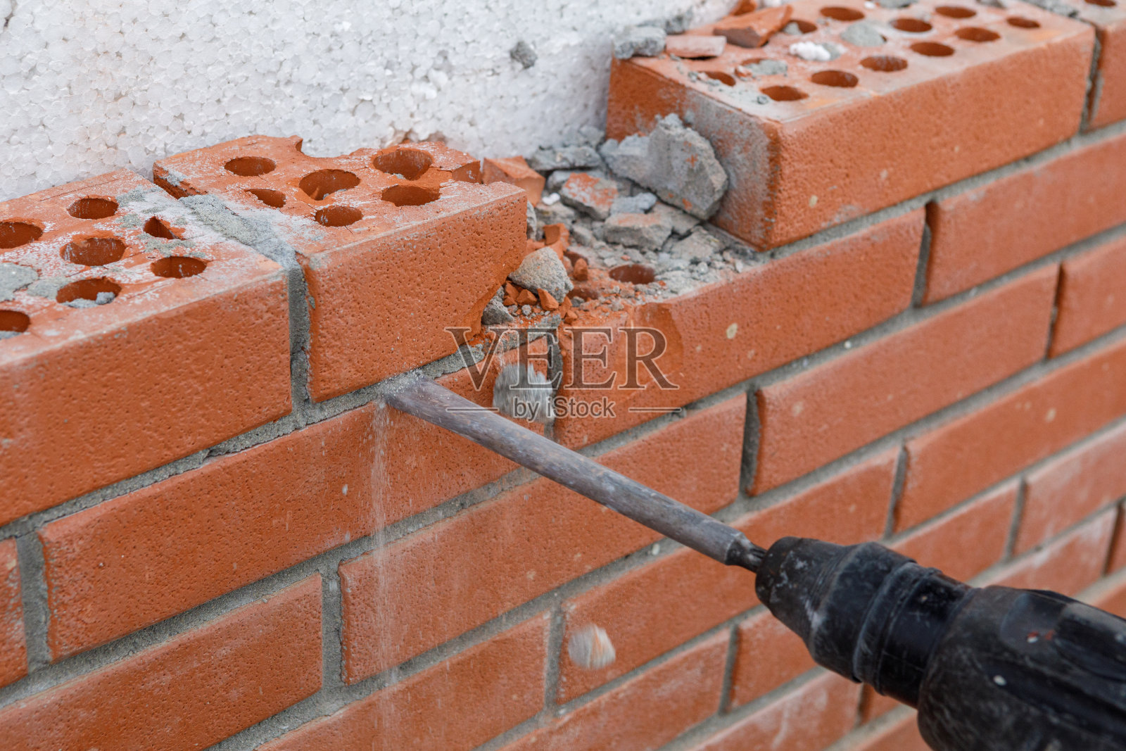 建筑工人用工具把墙的砖砌部分打碎照片摄影图片