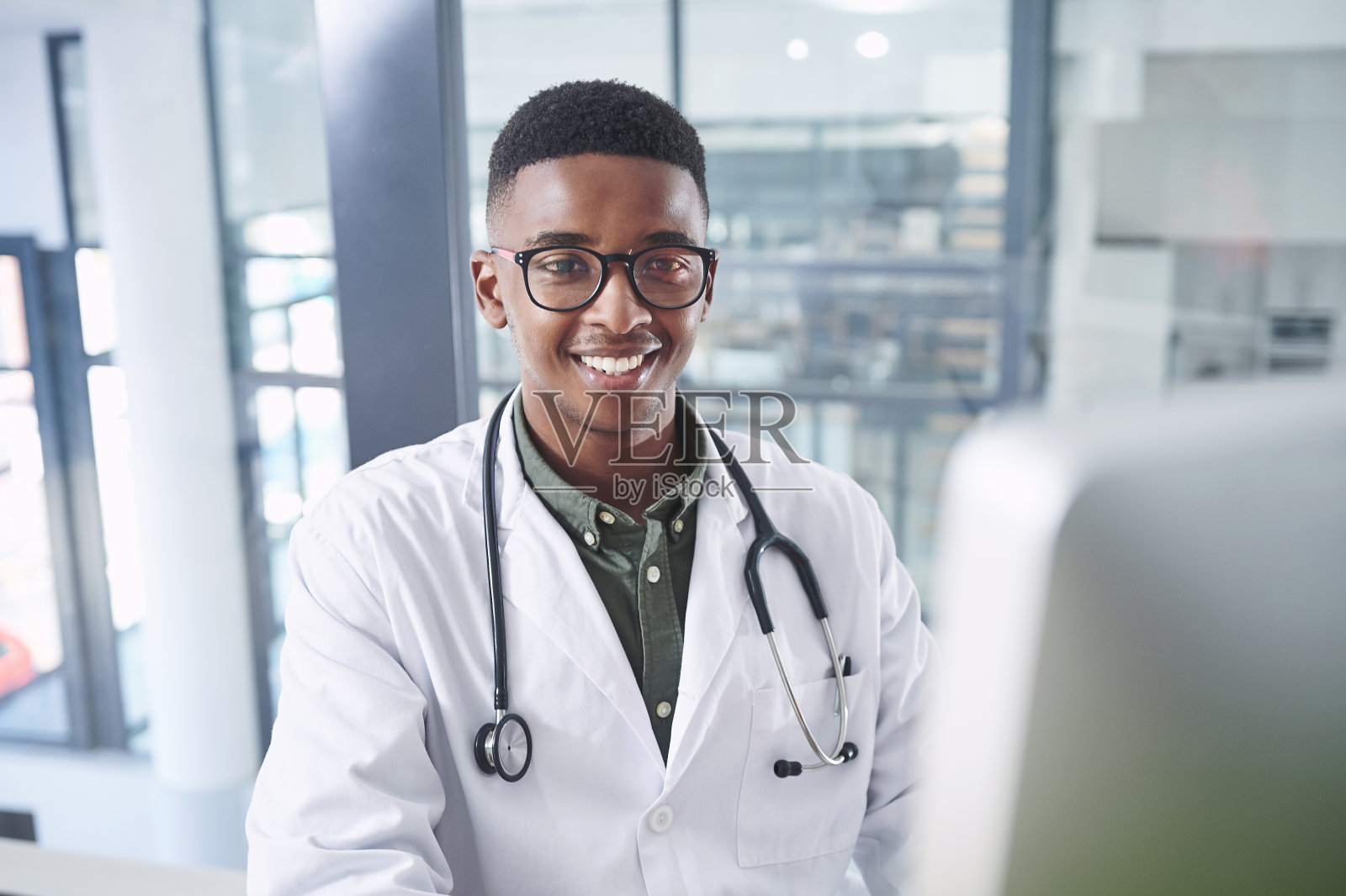 一个英俊的年轻医生独自坐在诊所的办公室里使用他的电脑照片摄影图片