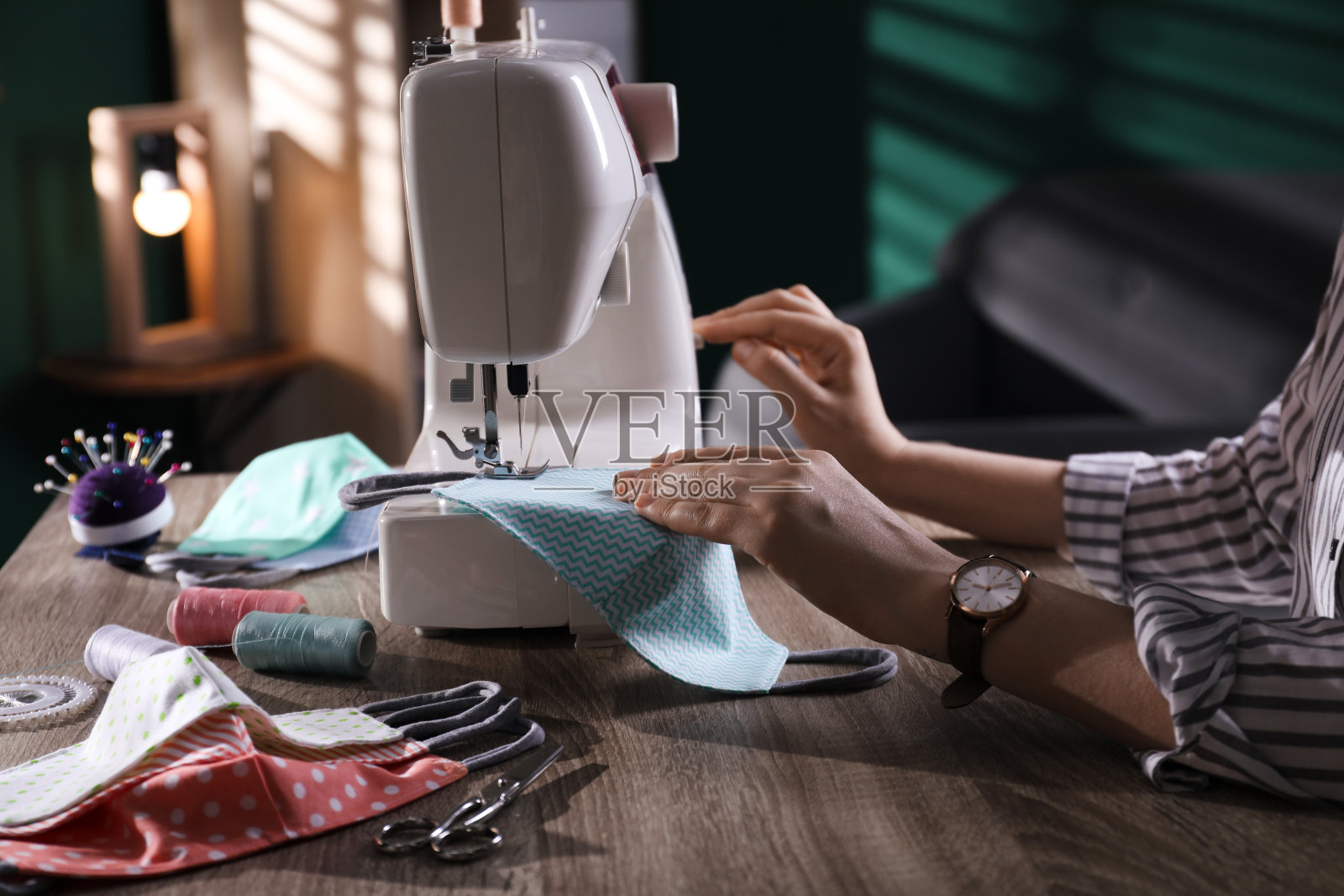 女工在室内用缝纫机缝布防护面罩，特写照片摄影图片