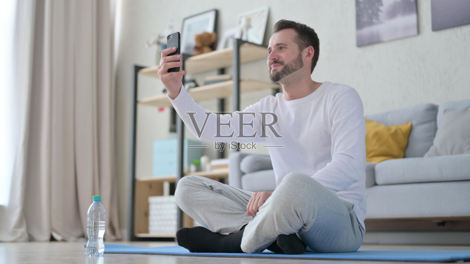 一名年轻人在瑜伽垫上用智能手机进行视频通话照片摄影图片