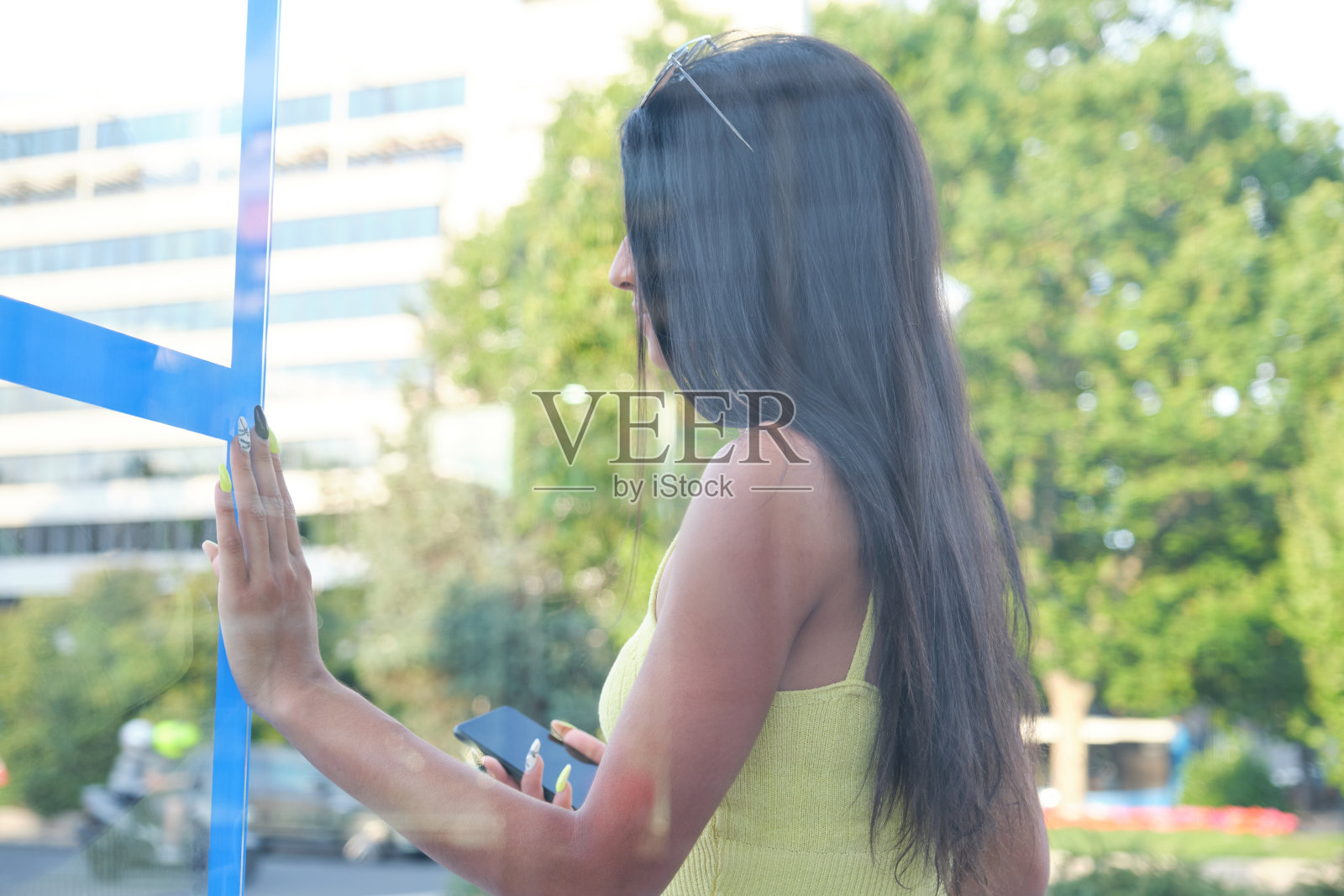 一个年轻的拉丁妇女在街上的公共汽车站等公共汽车。照片摄影图片