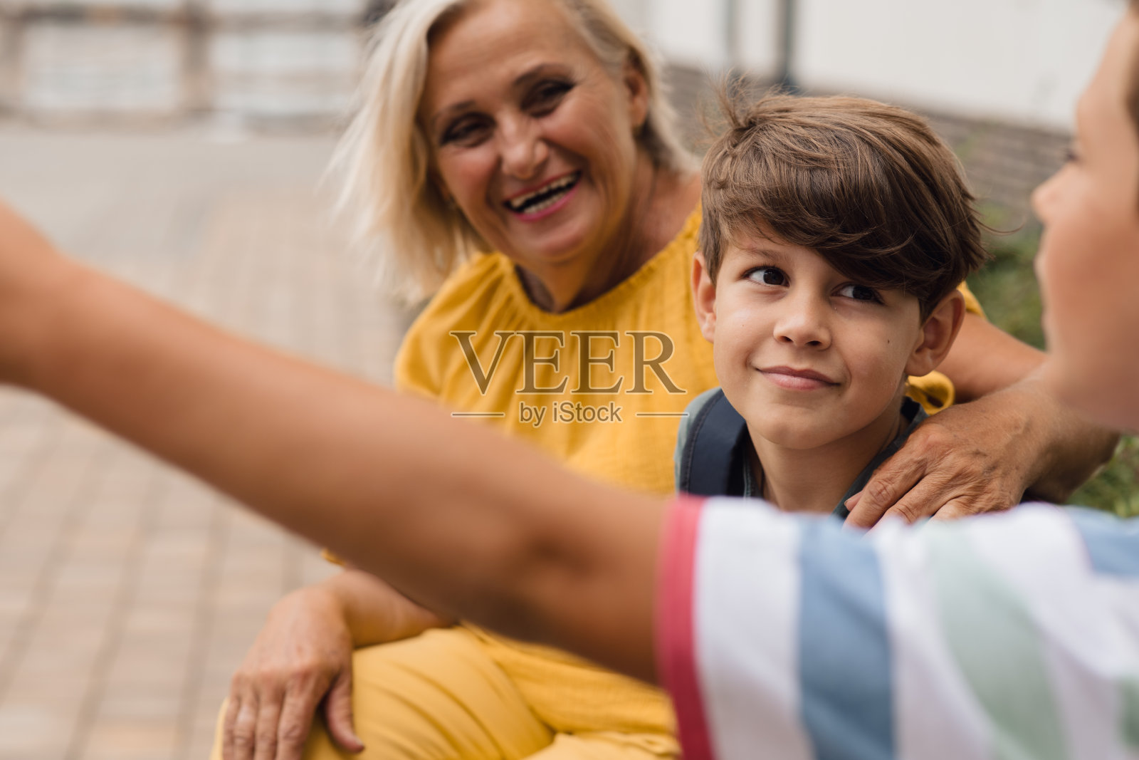 奶奶坐在准备上学的孙辈旁边。照片摄影图片