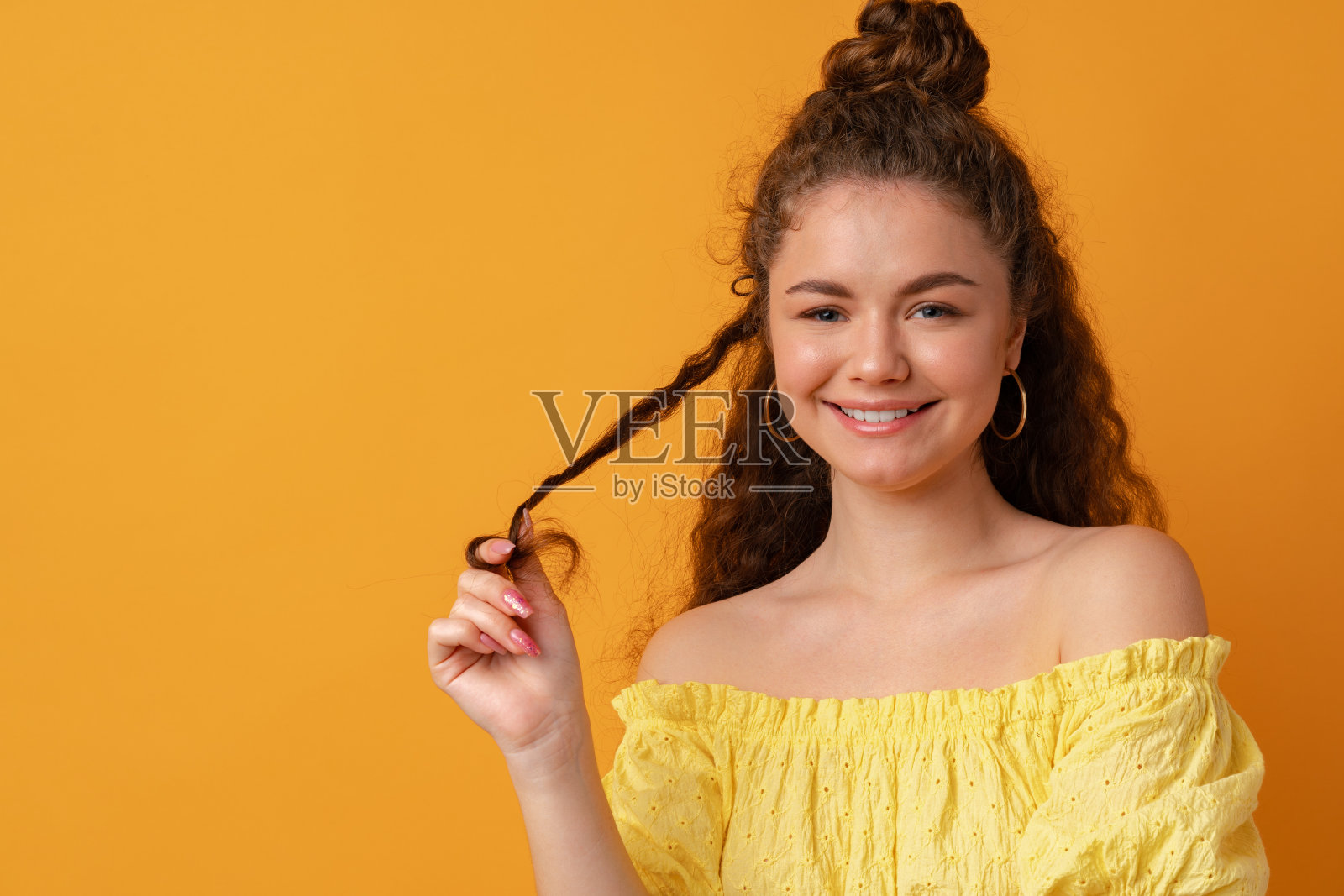 一个年轻的卷发女人的肖像在黄色的背景下照片摄影图片