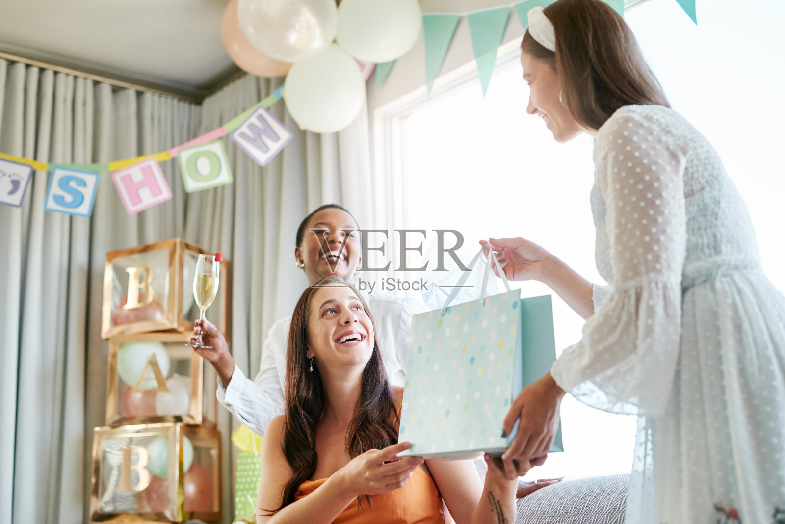 图为一位怀孕的母亲在宝宝送礼会上收到朋友们的礼物照片摄影图片