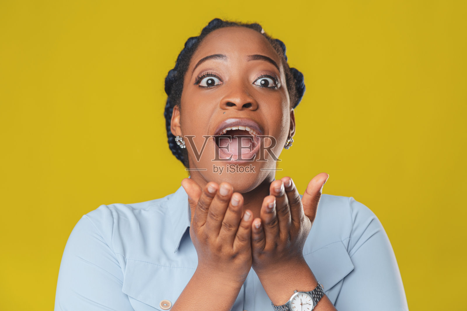 美丽的黑色头发的非洲裔美国女孩微笑着，在黄色的背景上惊奇地向不同的方向展开双臂照片摄影图片