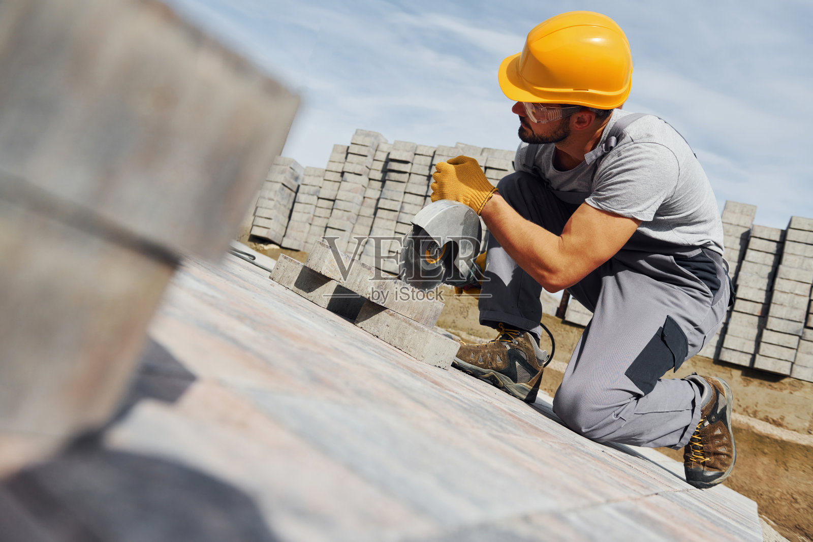 圆锯切片。男职工穿着黄色制服从事与路面有关的工作照片摄影图片