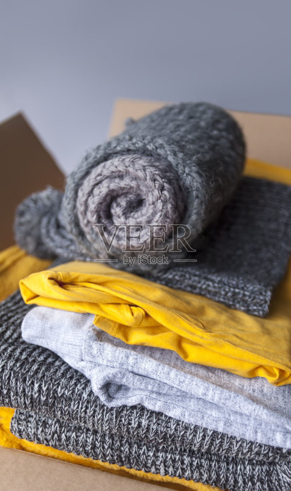 纸板箱里的衣服。黄色和灰色是流行的时尚色彩。卷t恤和套头衫。家庭衣柜紧凑型组织。家庭存储。照片摄影图片