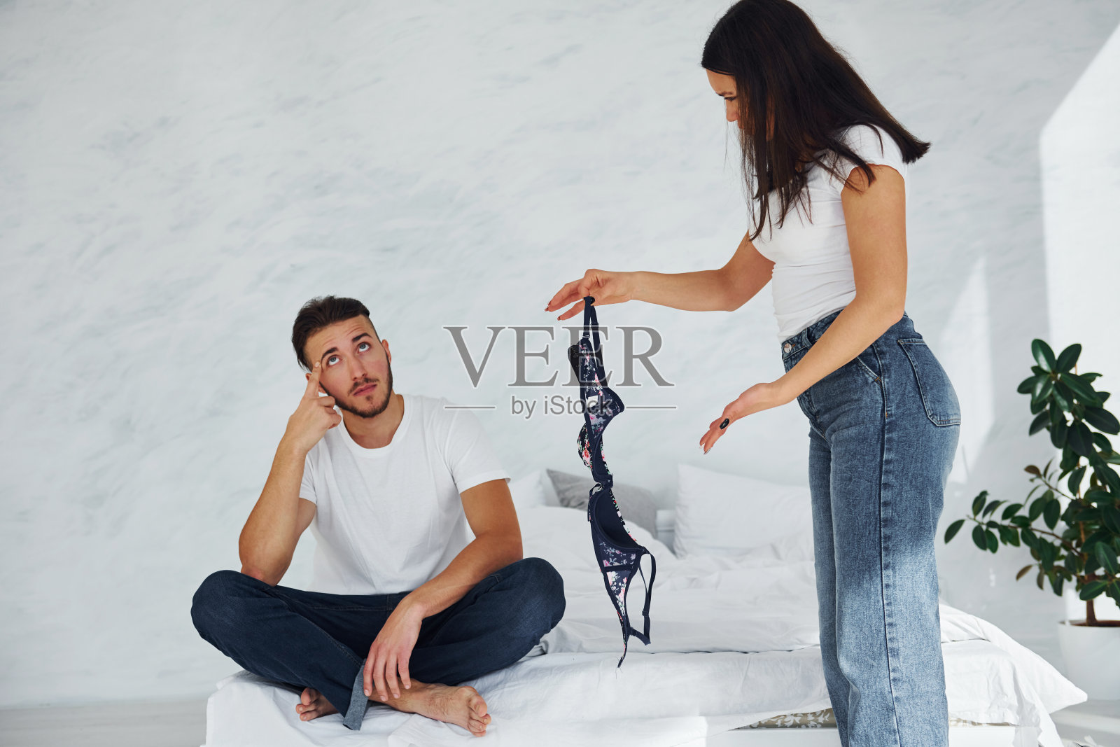 这个女孩被她的男朋友出卖了。家伙被抓住了。女人拿着别人的胸罩照片摄影图片