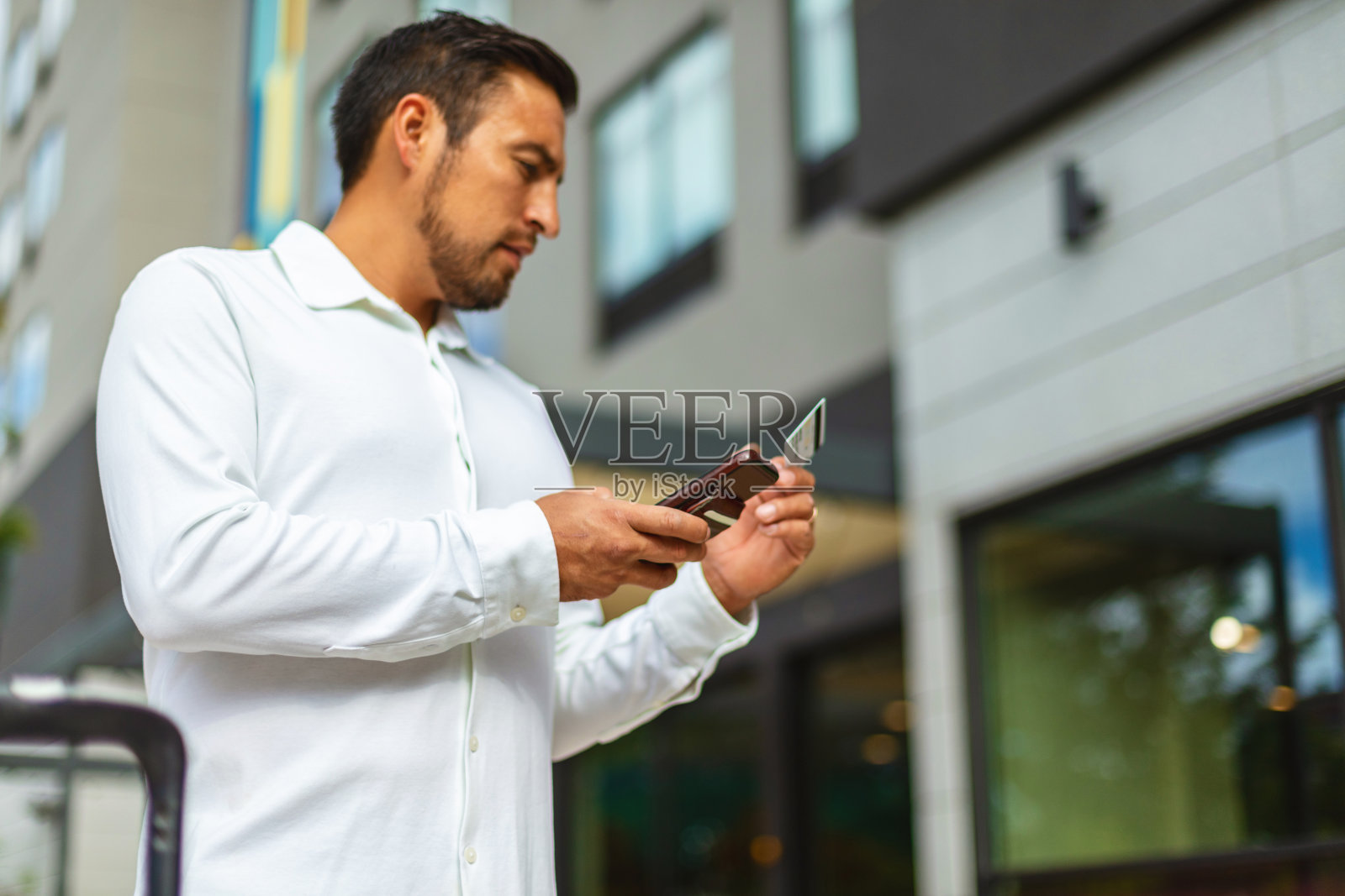 成年西班牙裔千禧一代男性在城市街道上使用电话进行网上银行交易旅行照片系列照片摄影图片