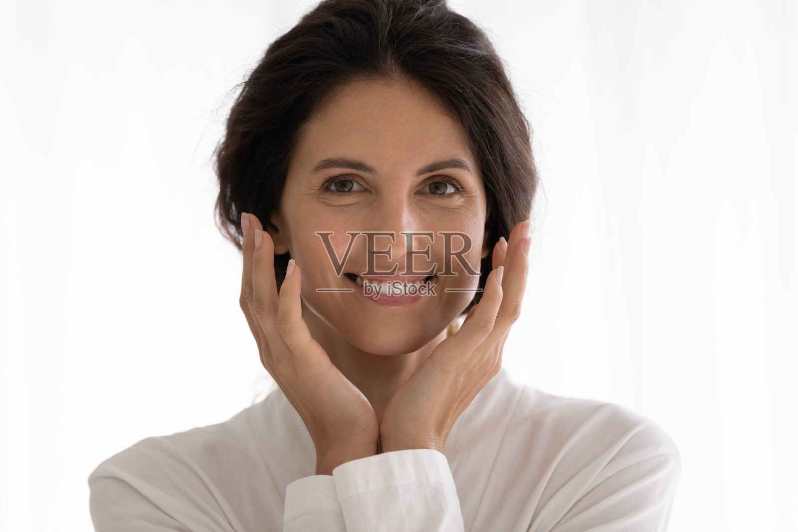 漂亮的年轻拉丁女人看着相机微笑触摸脸颊照片摄影图片