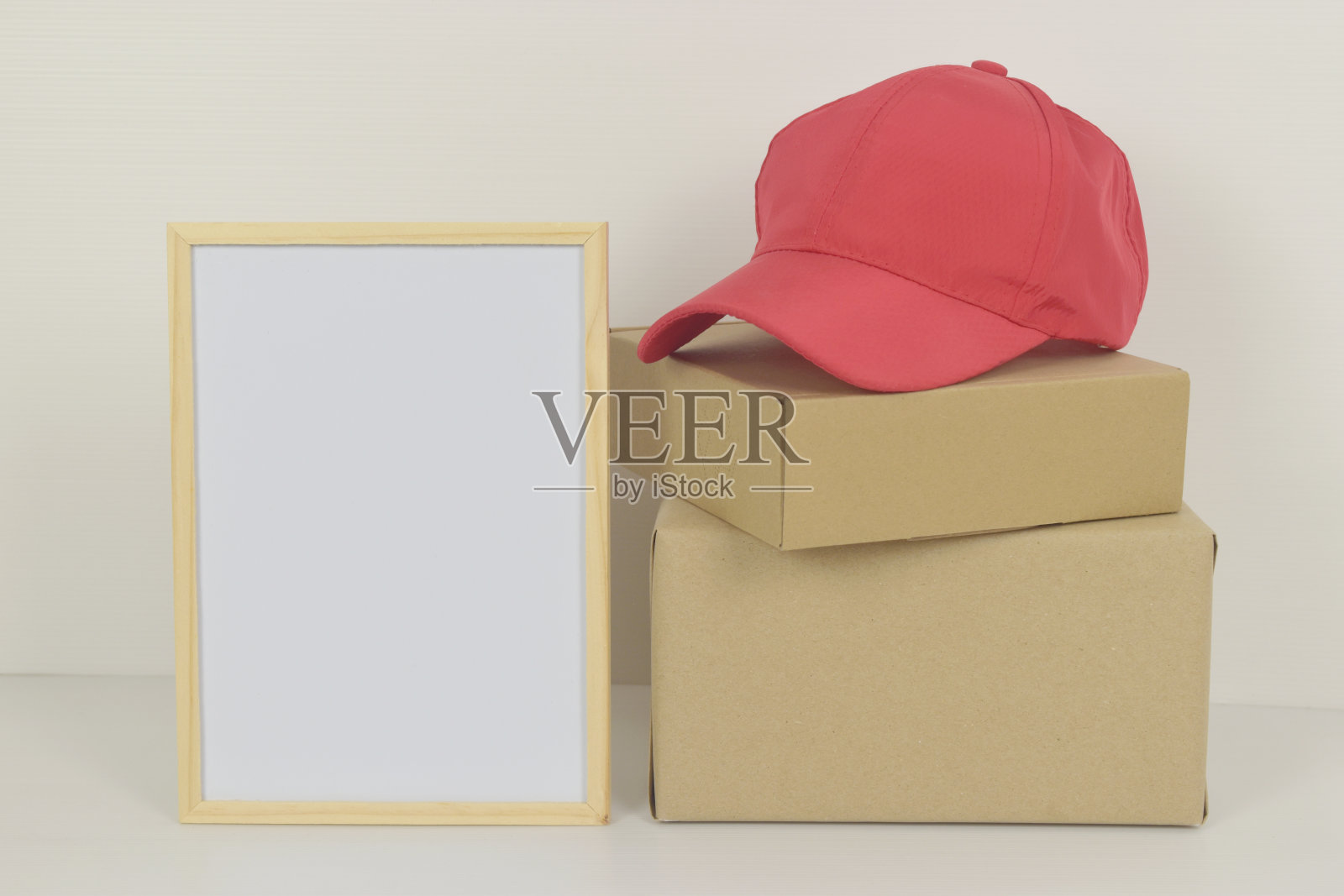 木制框架内的空白白板，边上有帽子和盒子。照片摄影图片
