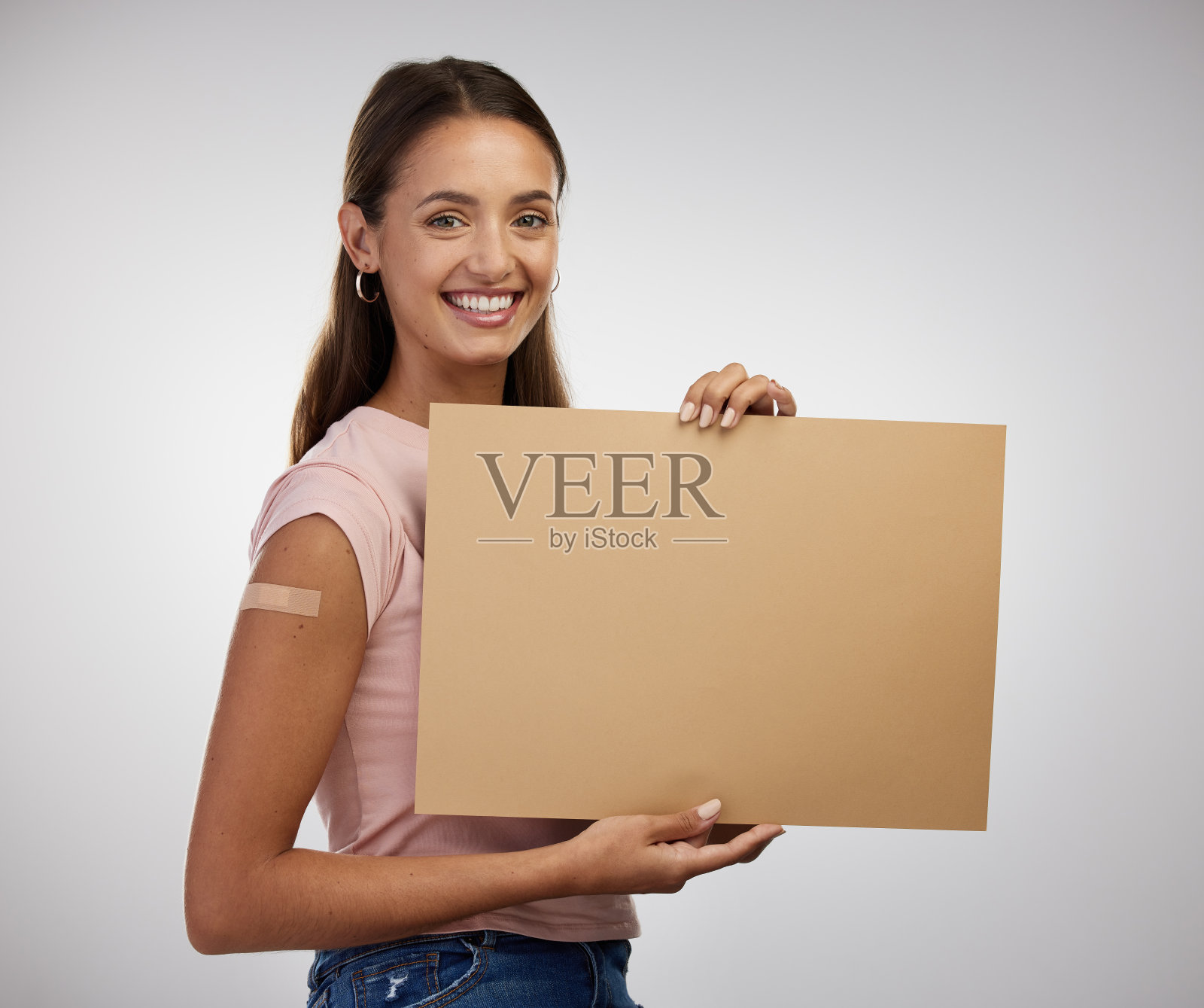 一名年轻女子在接种疫苗后独自站在演播室，手里拿着海报照片摄影图片