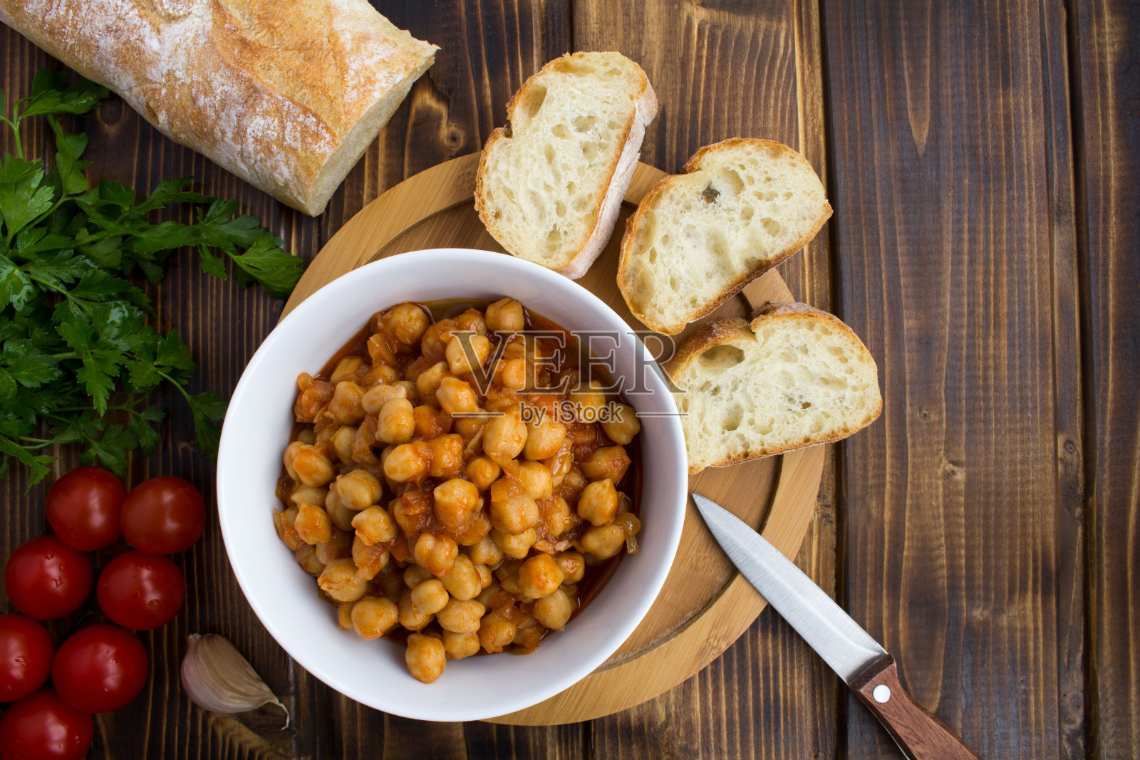 鹰嘴豆和番茄酱放在白色的碗里，法棍放在木制的背景上照片摄影图片