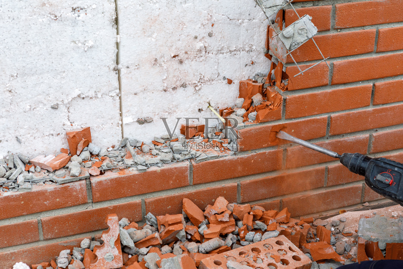 建筑工人用工具把墙的砖砌部分打碎照片摄影图片