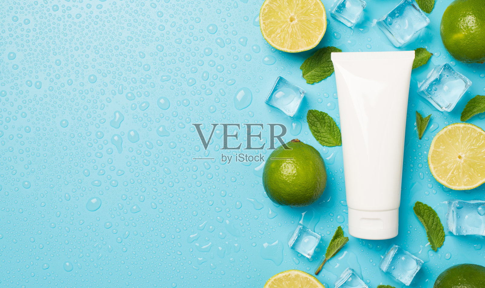 上面的照片是一堆酸橙，冰块，薄荷，和一管奶油孤立在蓝色的背景与空白照片摄影图片