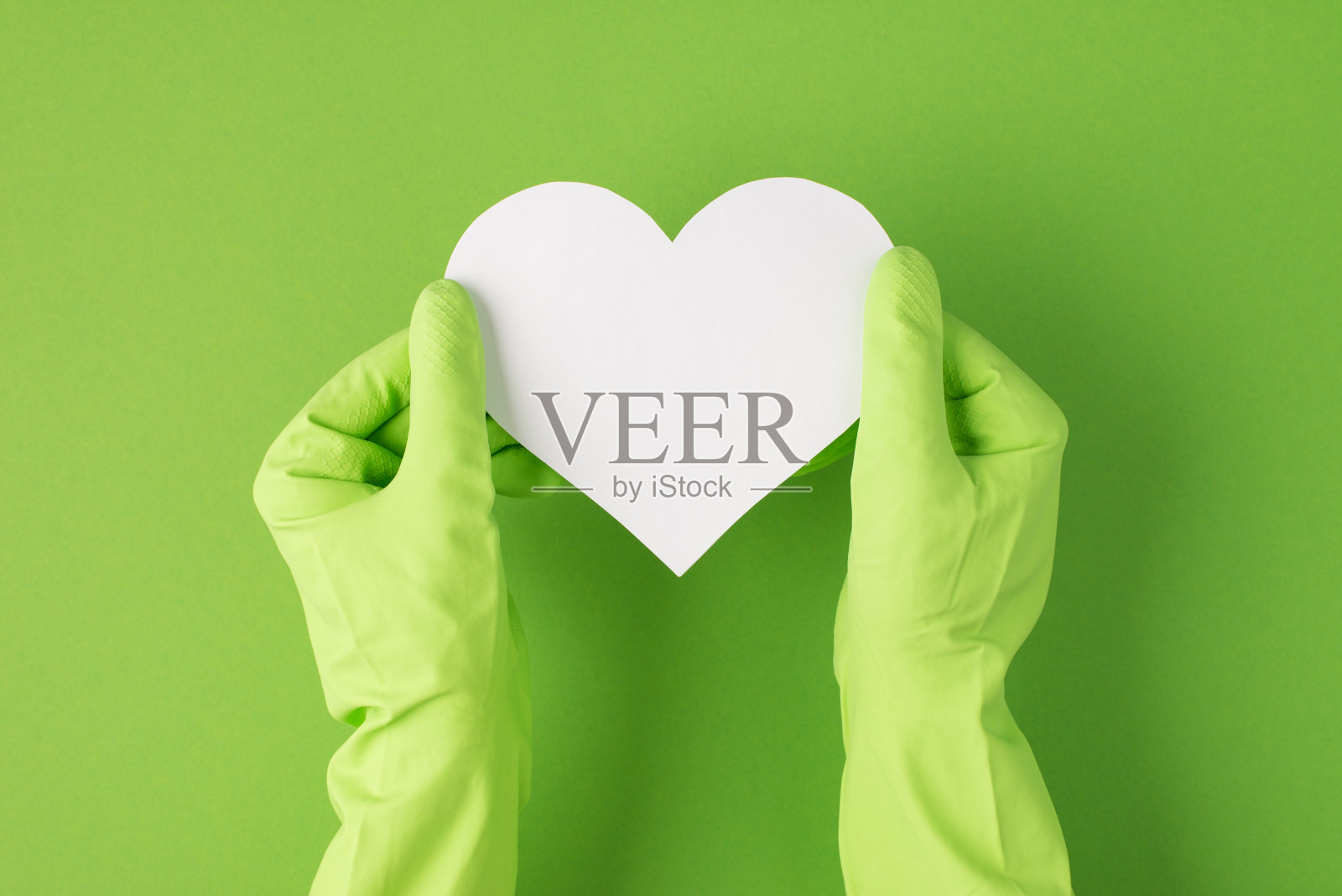 俯视图照片双手在绿色橡胶手套手持白纸心与孤立的绿色背景空白照片摄影图片