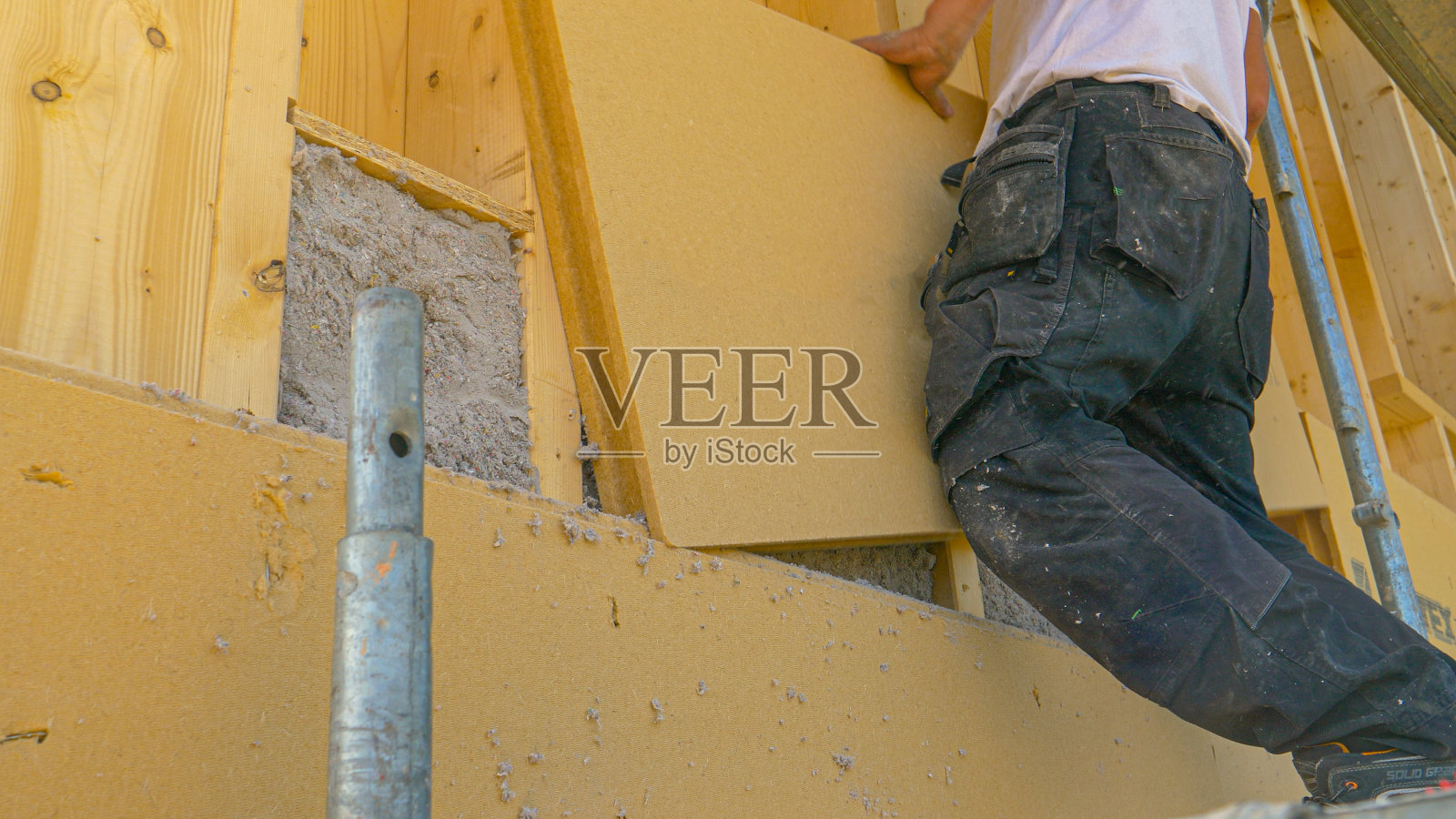 接近:承包商在充满纤维素的墙上铺设隔热板。照片摄影图片