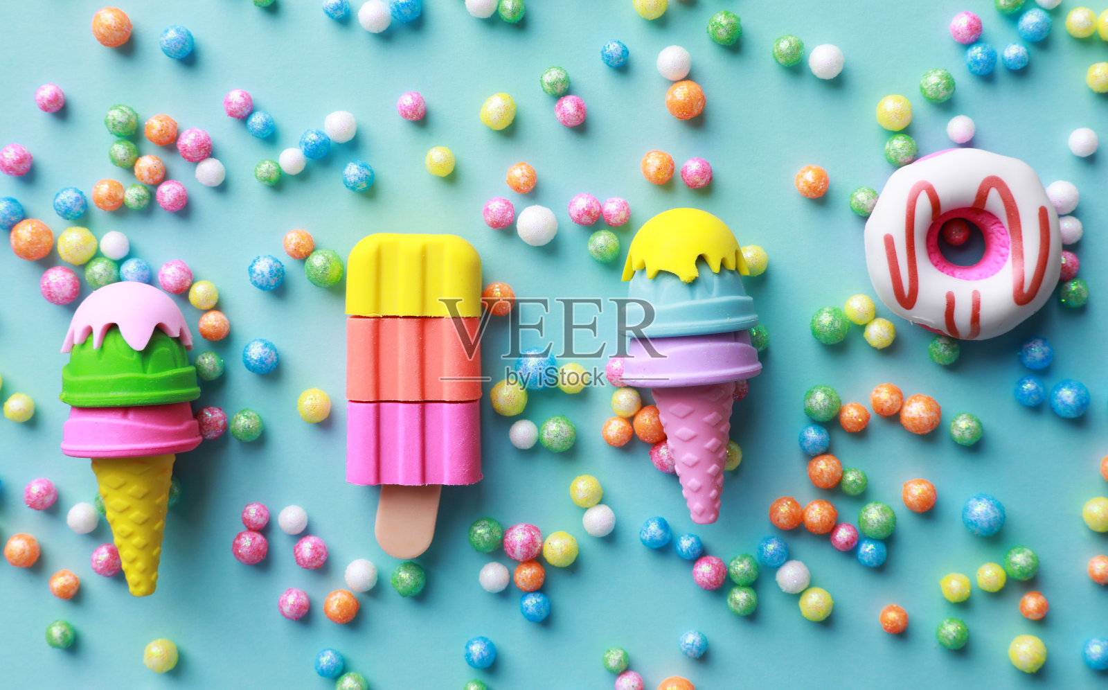 玩具冰淇淋、甜甜圈和绿松石背景上的珠子，平躺着照片摄影图片