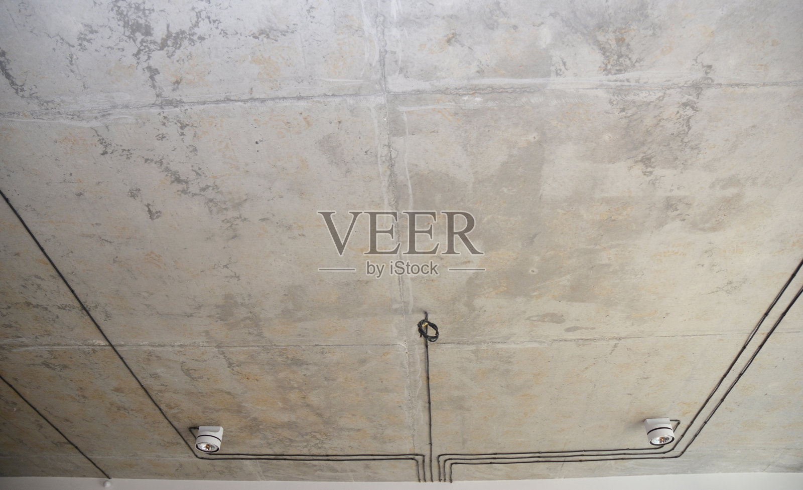 带有阁楼式天花板和照明的现代室内设计。混凝土天花板，黑色电线和吊灯悬挂在绳子上。照片摄影图片