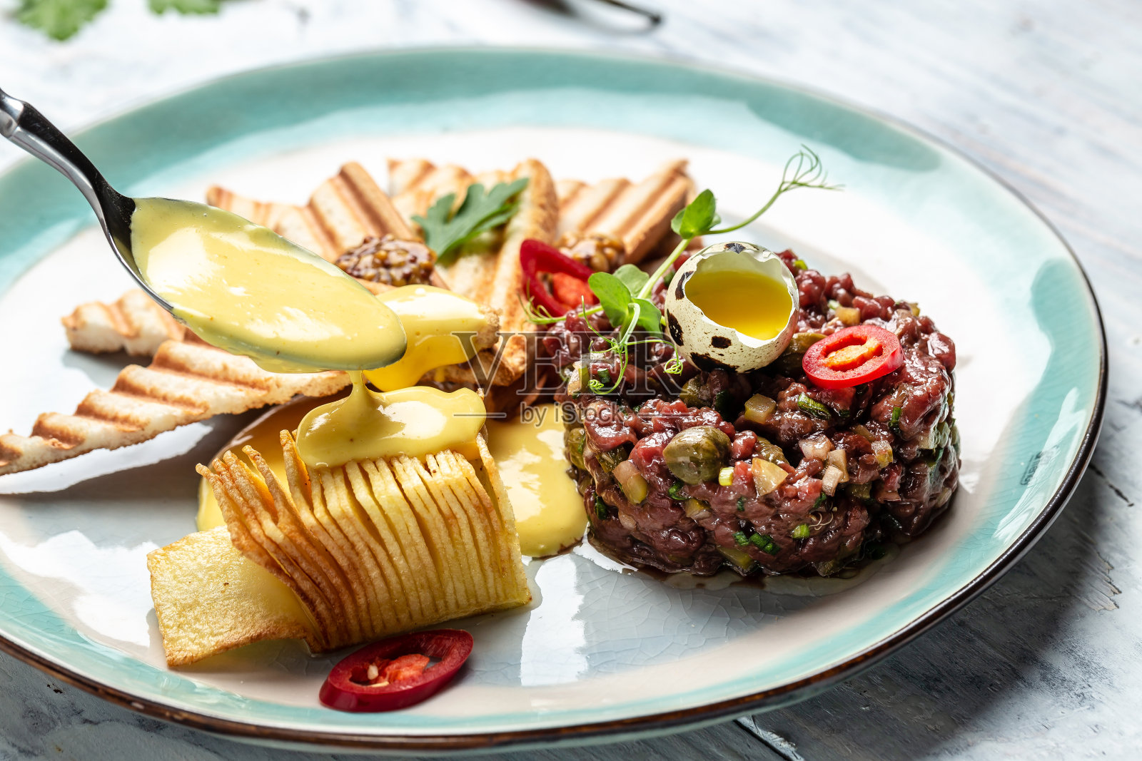 法国料理:鞑靼牛排配生鹌鹑蛋黄，酸豆，腌黄瓜配面包吐司。食品配方的背景。近距离照片摄影图片