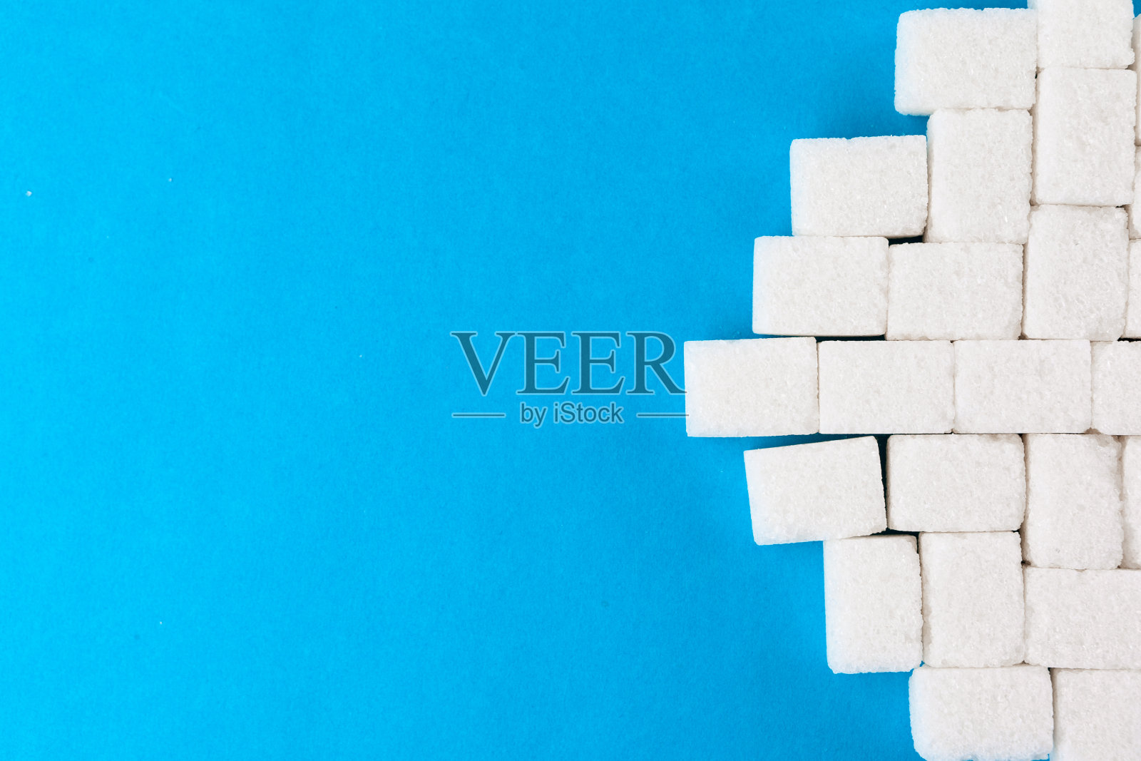 亮蓝色背景上的白糖块照片摄影图片