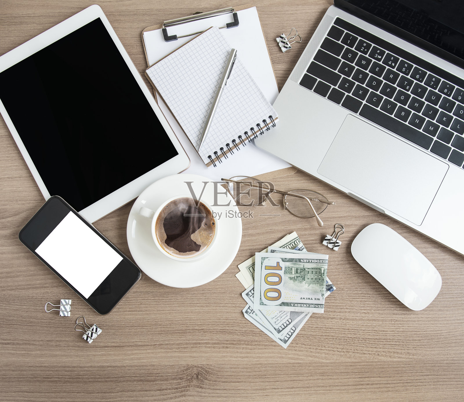 桌上放着办公用品和钱的笔记本电脑。照片摄影图片