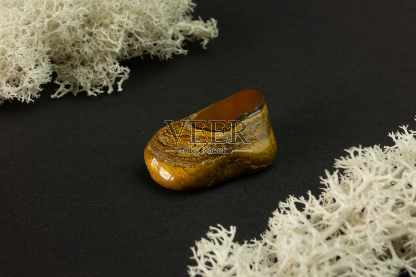 老虎的眼睛石来自南非共和国RSA。黑色背景上的天然矿石。矿物学，地质学，魔法石，半宝石，矿物样品。特写宏观照片。照片摄影图片