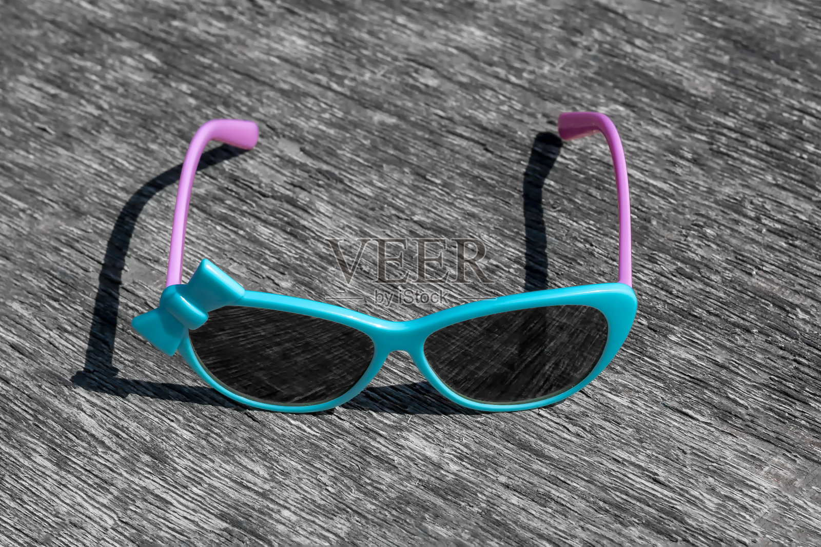 灰色背景上有粉红色拱门的蓝色太阳镜。照片摄影图片