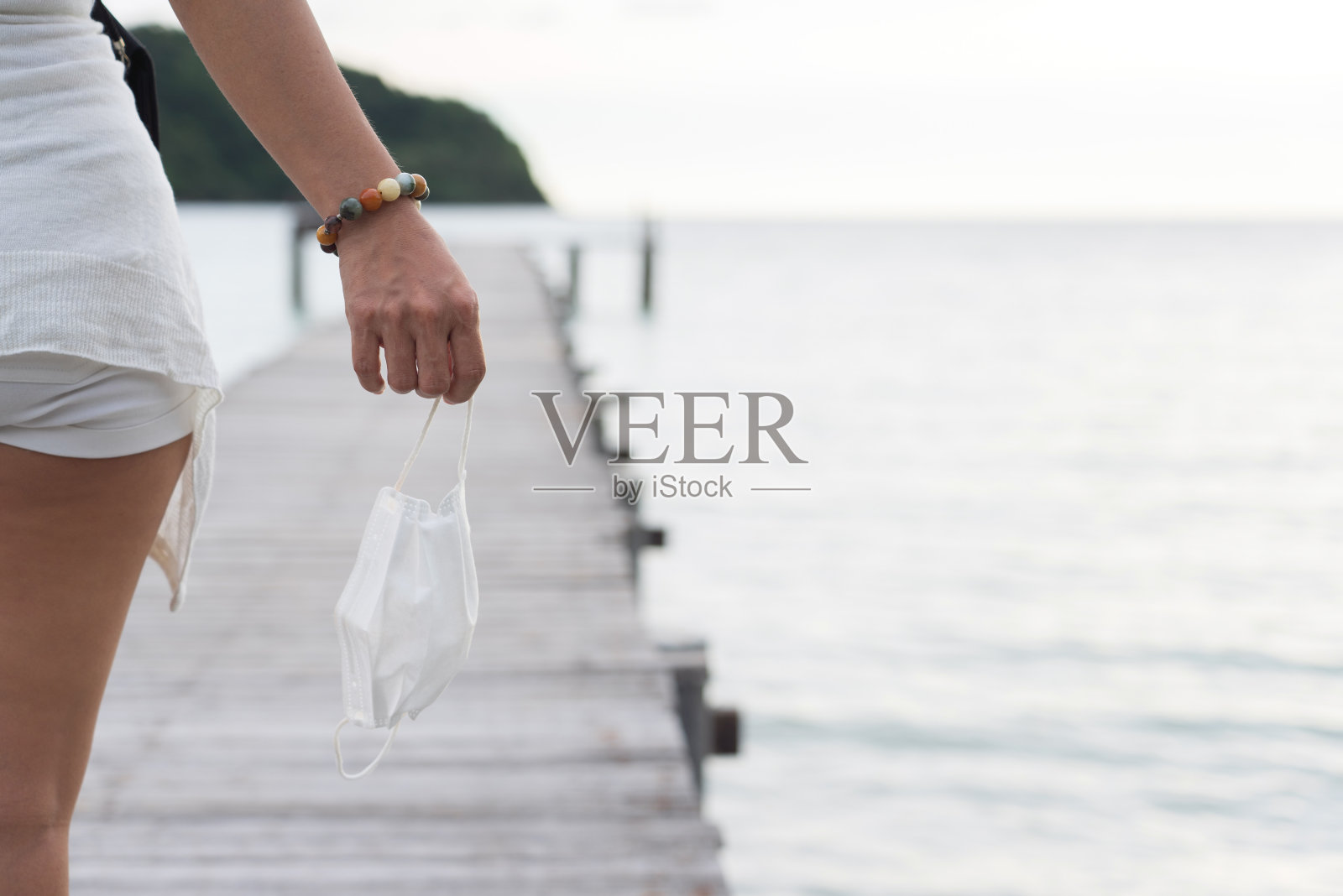 亚洲女性手持面罩与码头和大海照片摄影图片