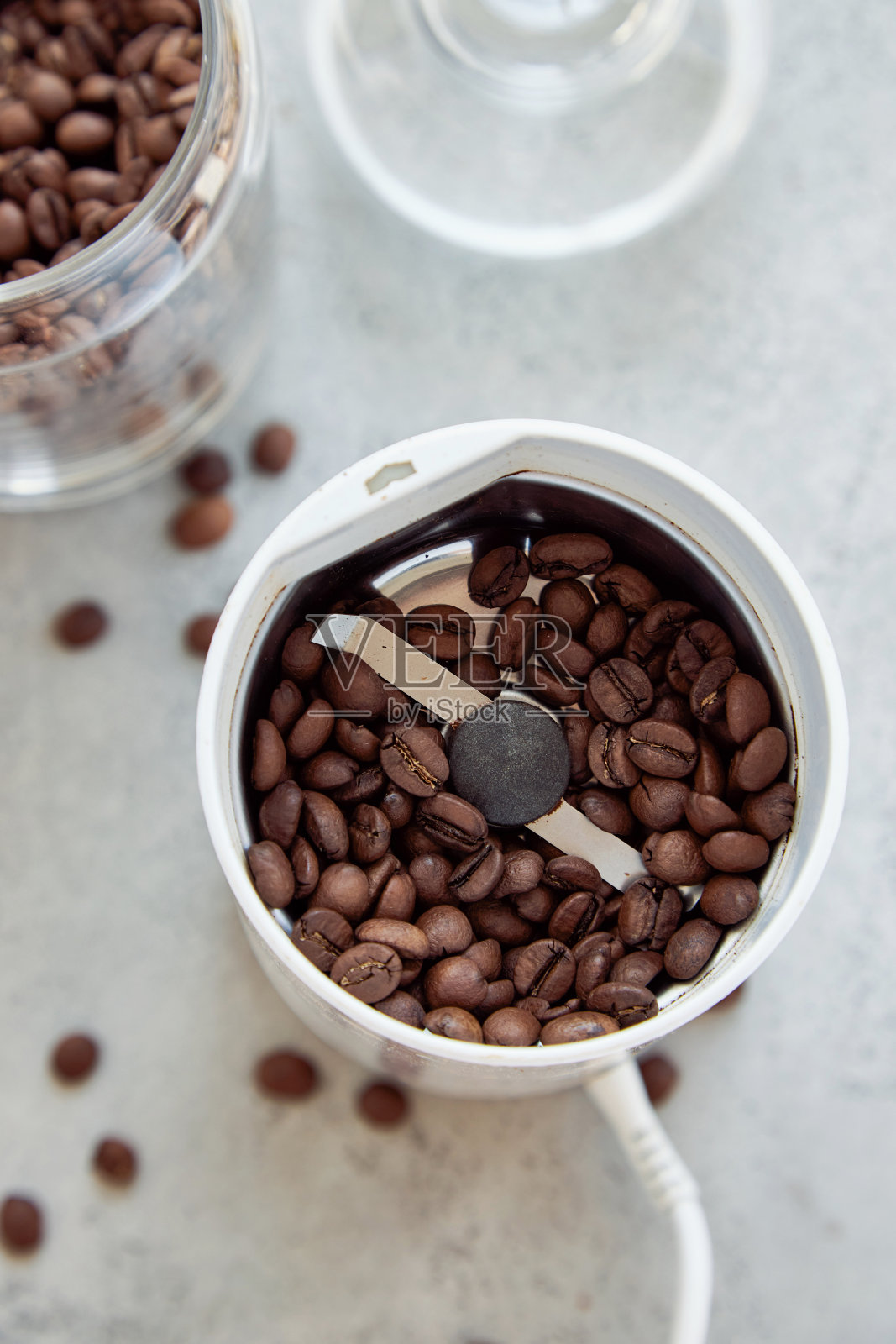 白色石桌上有一个装有咖啡豆的咖啡研磨机和一个装有咖啡豆的玻璃容器照片摄影图片