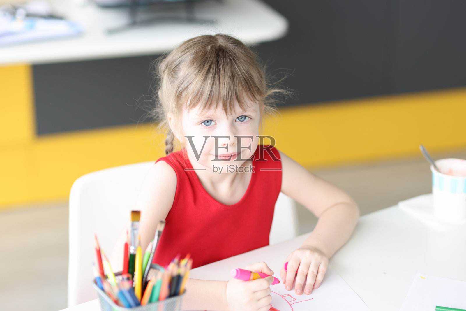 小女孩用彩色铅笔在纸上画画照片摄影图片