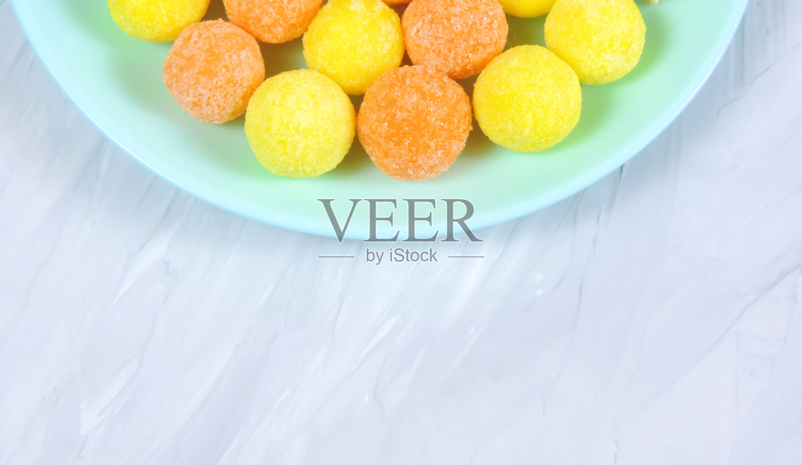 不同颜色的上釉花生放在盘子里，白色背景。五彩缤纷的花生。特写镜头。小吃彩色仁，榛子，果仁。照片摄影图片