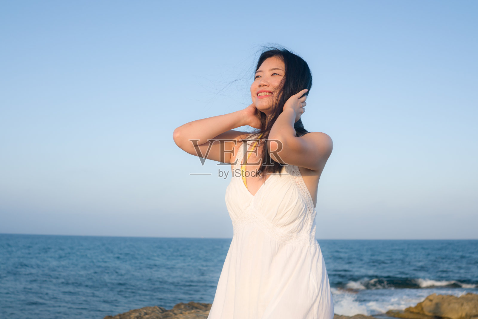 度假生活方式的年轻亚洲女人的海边肖像-快乐和美丽的韩国女孩享受海滩度假旅行轻松和愉快的海滩岩石悬崖照片摄影图片