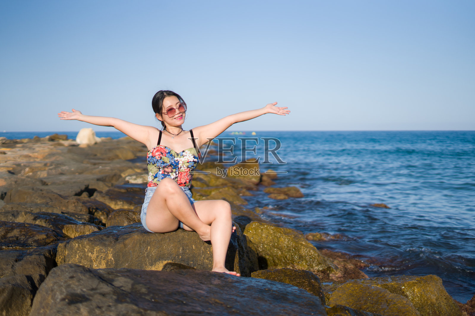 度假生活方式的年轻亚洲女人的海边肖像-快乐和美丽的韩国女孩享受海滩度假旅行轻松和愉快的海滩岩石悬崖照片摄影图片