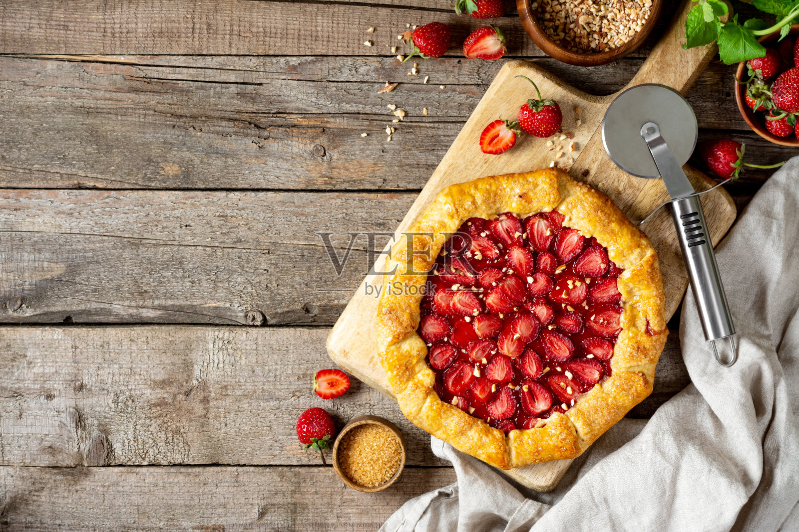法式煎蛋饼或派与草莓和杏仁在一个木制的服务板在烹饪的背景顶部视图与copyspace。夏日自制甜饼照片摄影图片