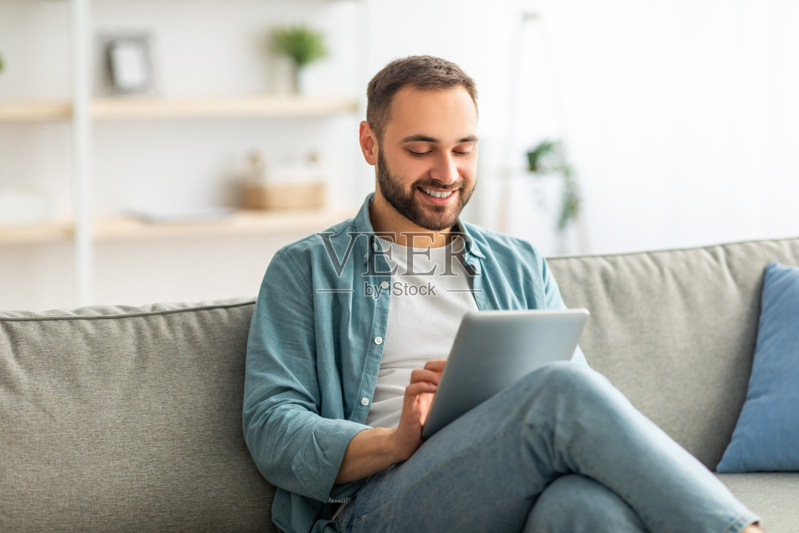 快乐的千禧一代，坐在沙发上用平板电脑，在家工作或上网学习照片摄影图片