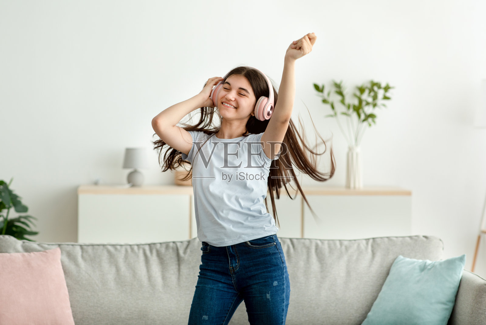 快乐的印度少女戴着耳机在家跳舞照片摄影图片