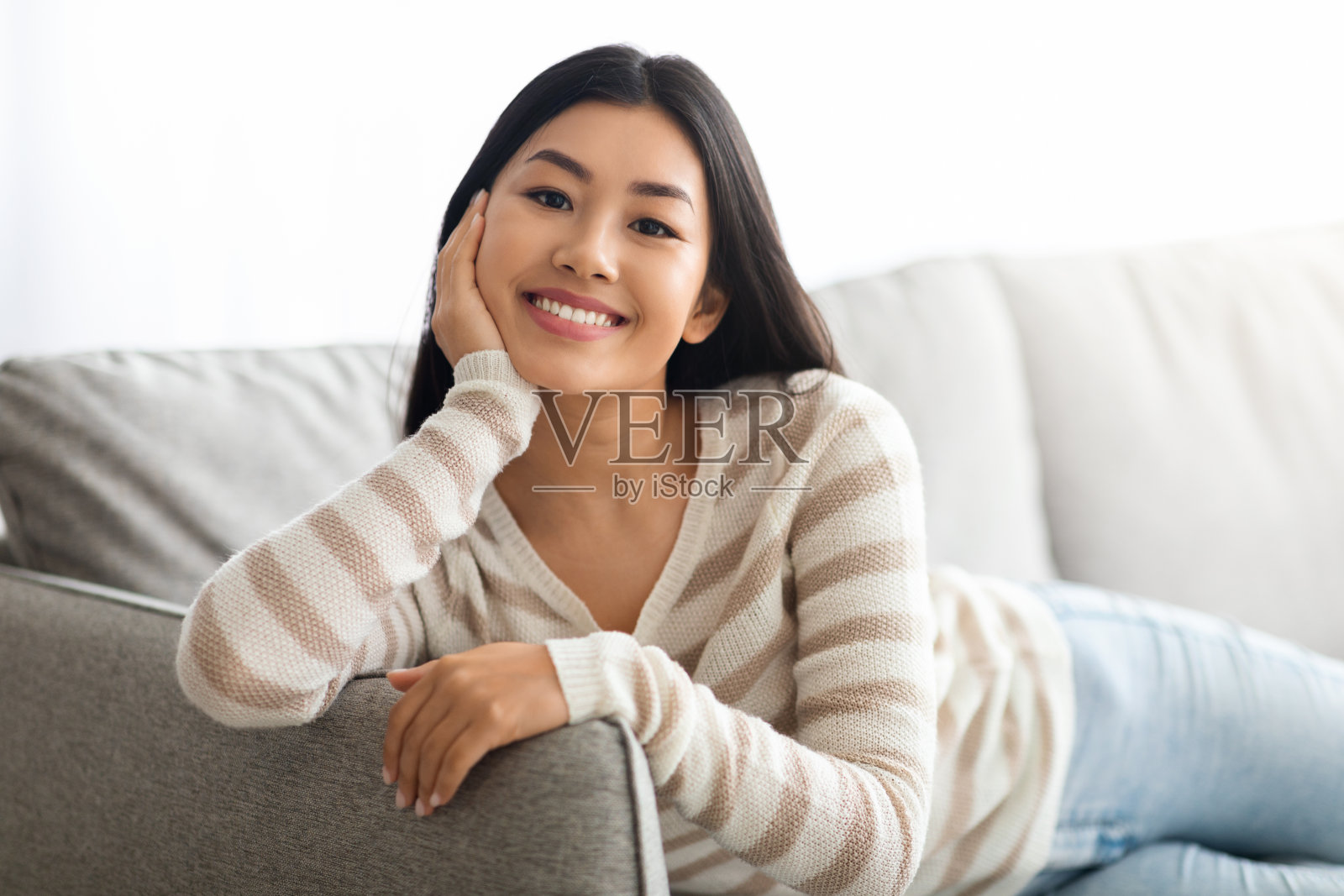 年轻快乐的亚洲女人在客厅沙发上休息的肖像照片摄影图片