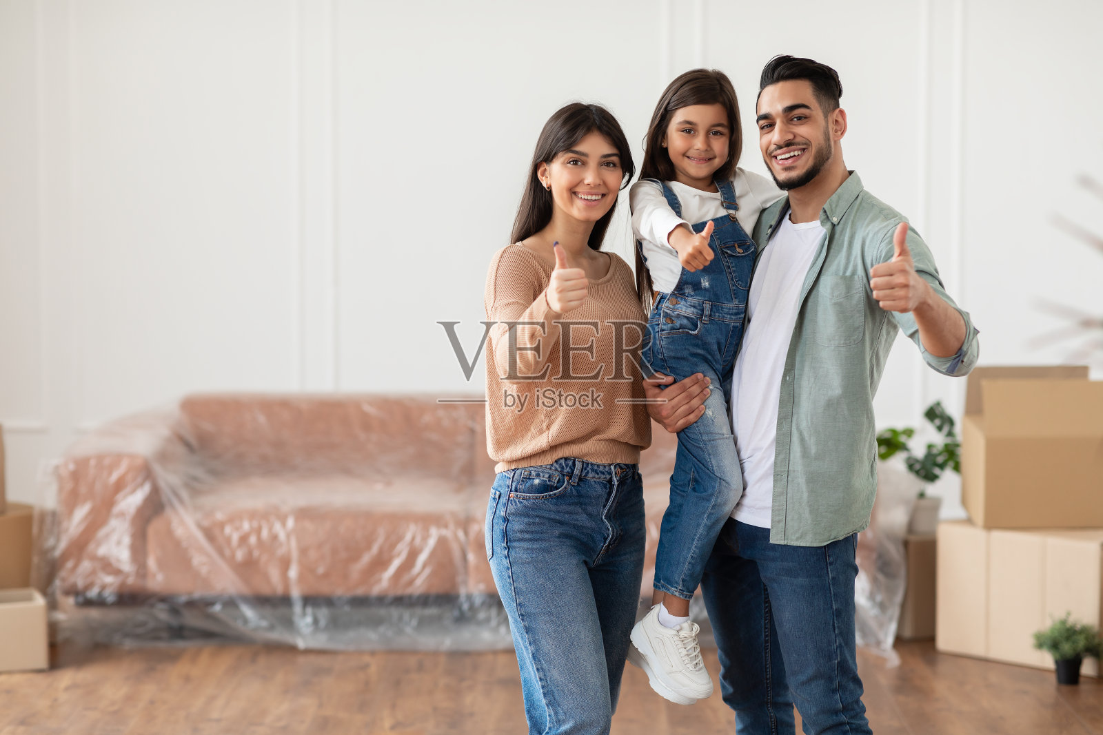 搬家日：快乐的一家人对着镜头竖起大拇指照片摄影图片