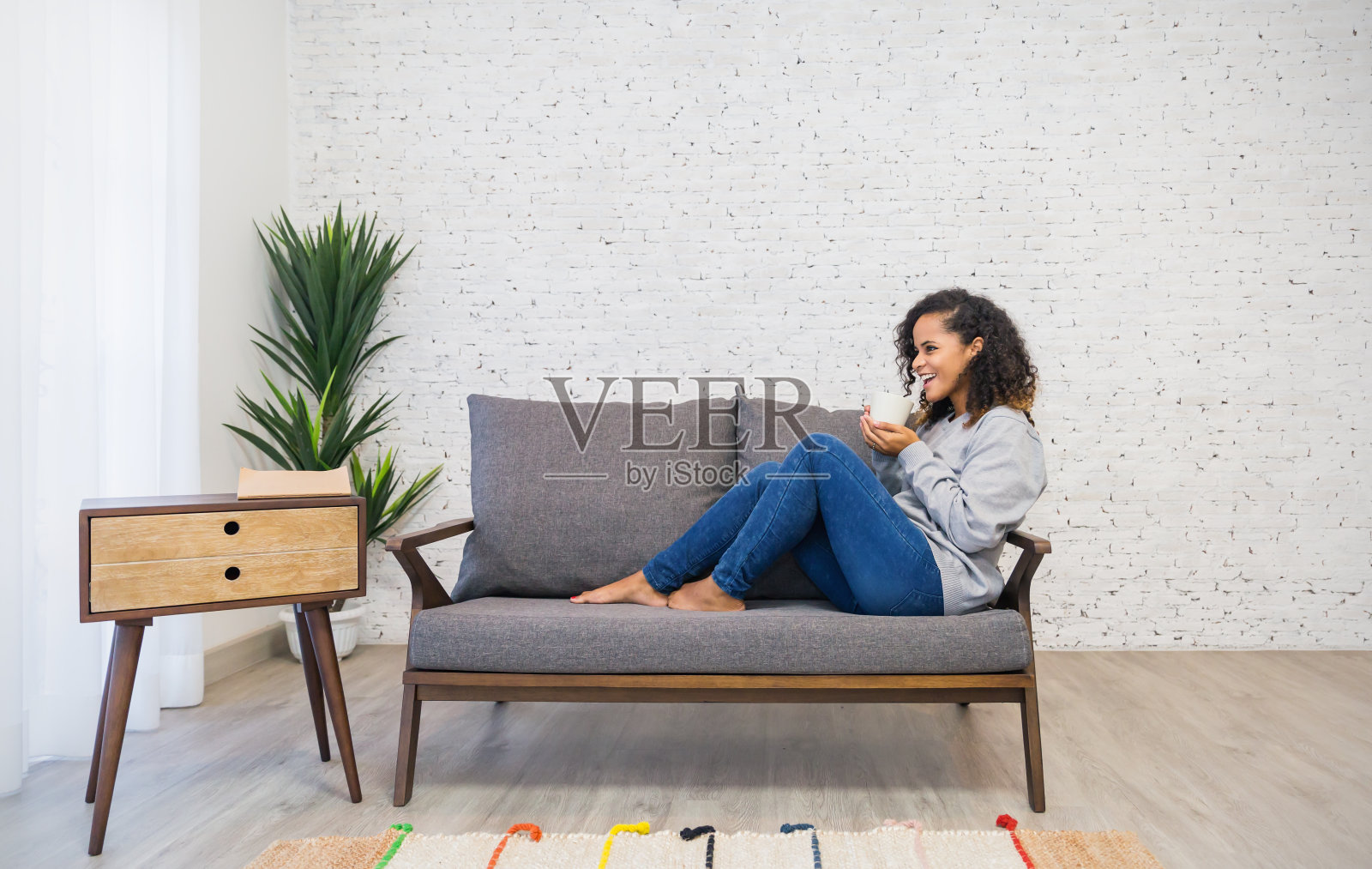 美丽的黑人女性肖像在沙发上喝着咖啡放松地睡觉。女孩假期早上或休息日在家里客厅放松。生活方式快乐和平理念照片摄影图片