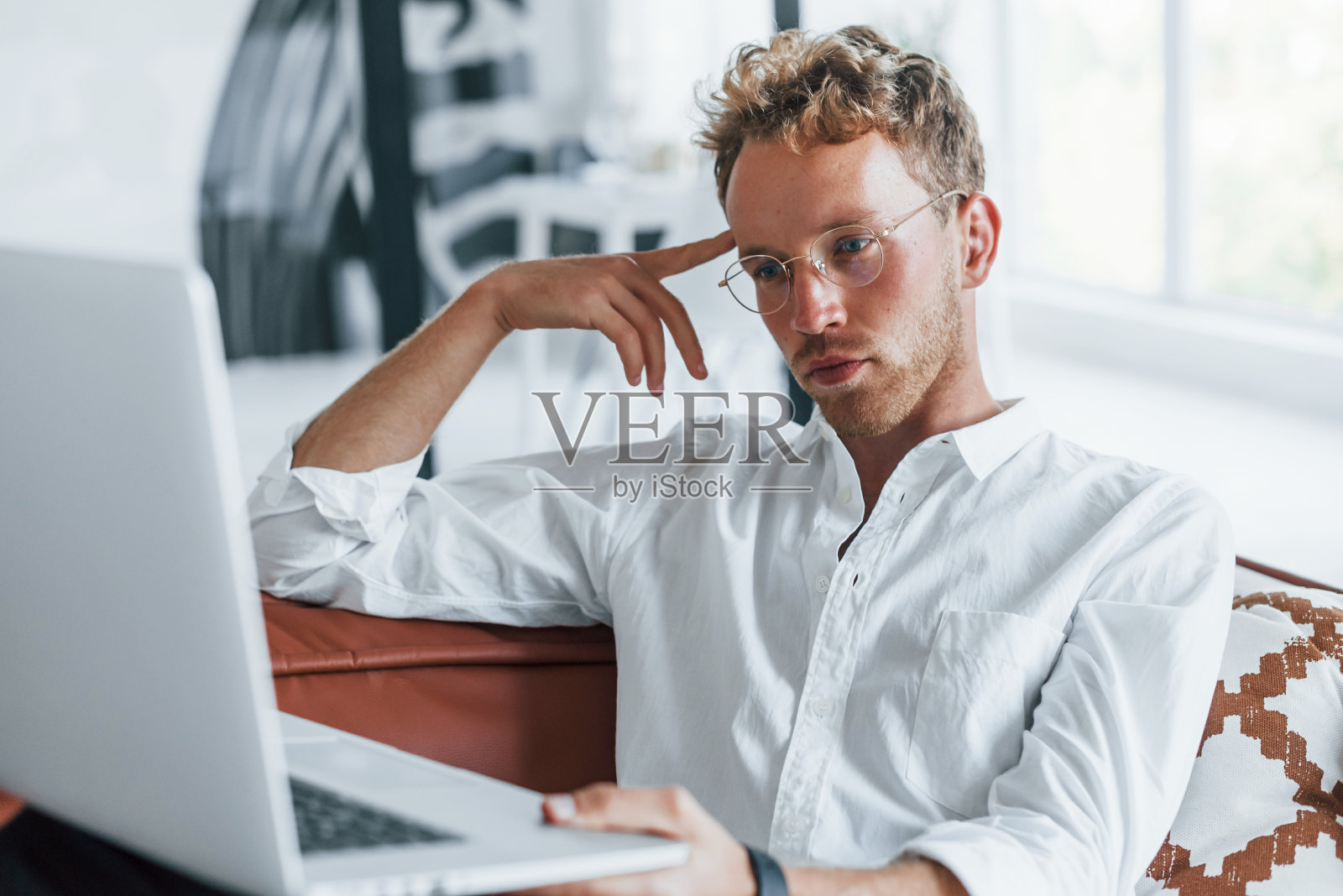 使用笔记本电脑。白种年轻人穿着优雅的白衬衫在家里照片摄影图片