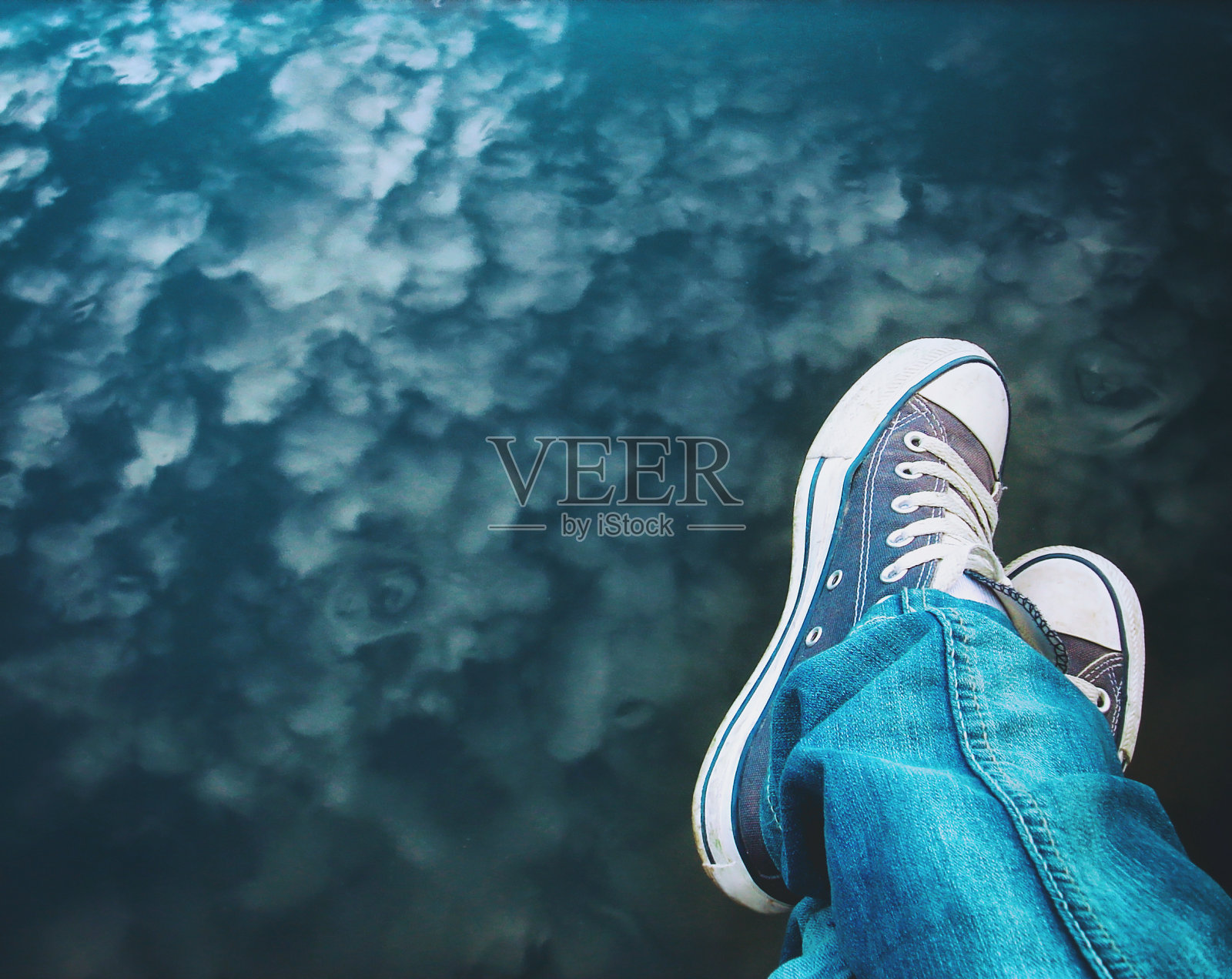 穿着运动鞋的女性脚和水中倒映的美丽云景照片摄影图片
