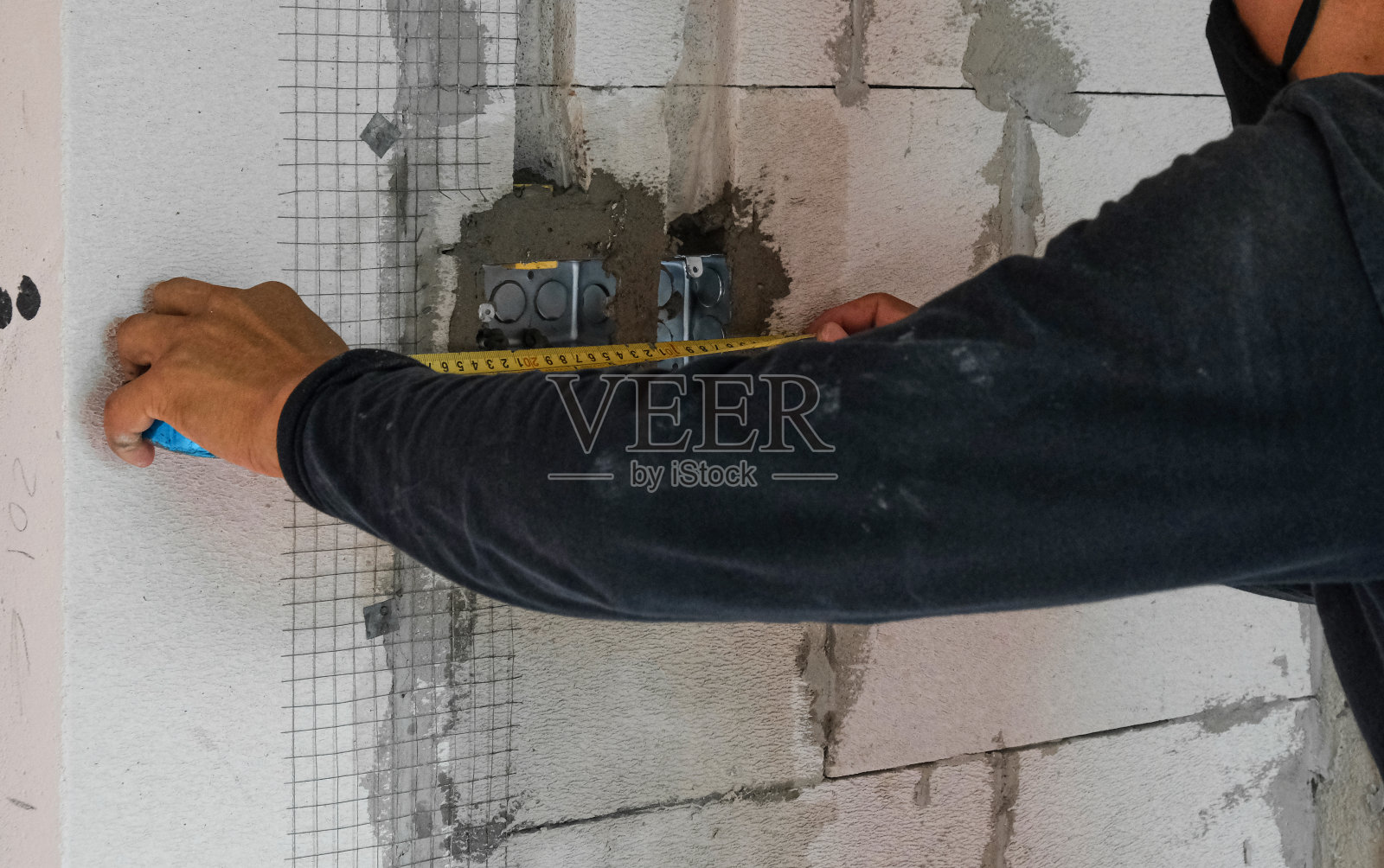 电工男工作测量准备安装电线电源线。专业技术人员在吊顶水泥梁上设置接电金属盒照片摄影图片