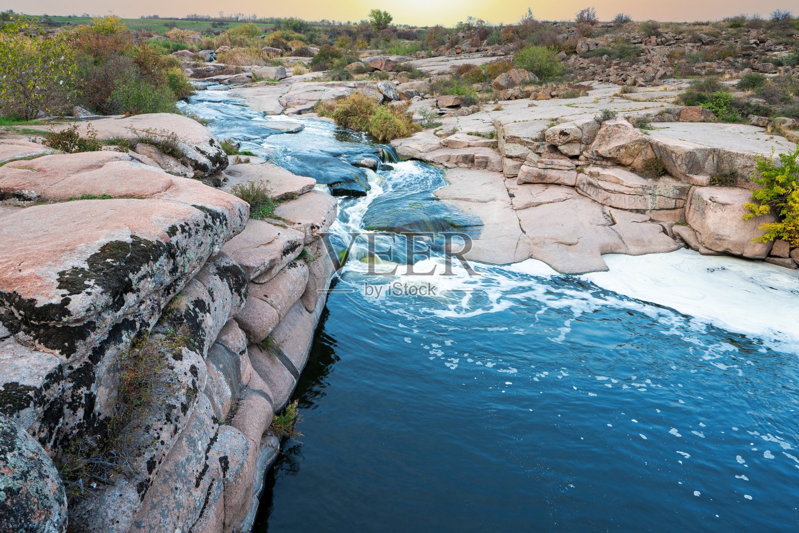 一条闪光的小溪在光滑、潮湿、黑暗的石头间流淌照片摄影图片