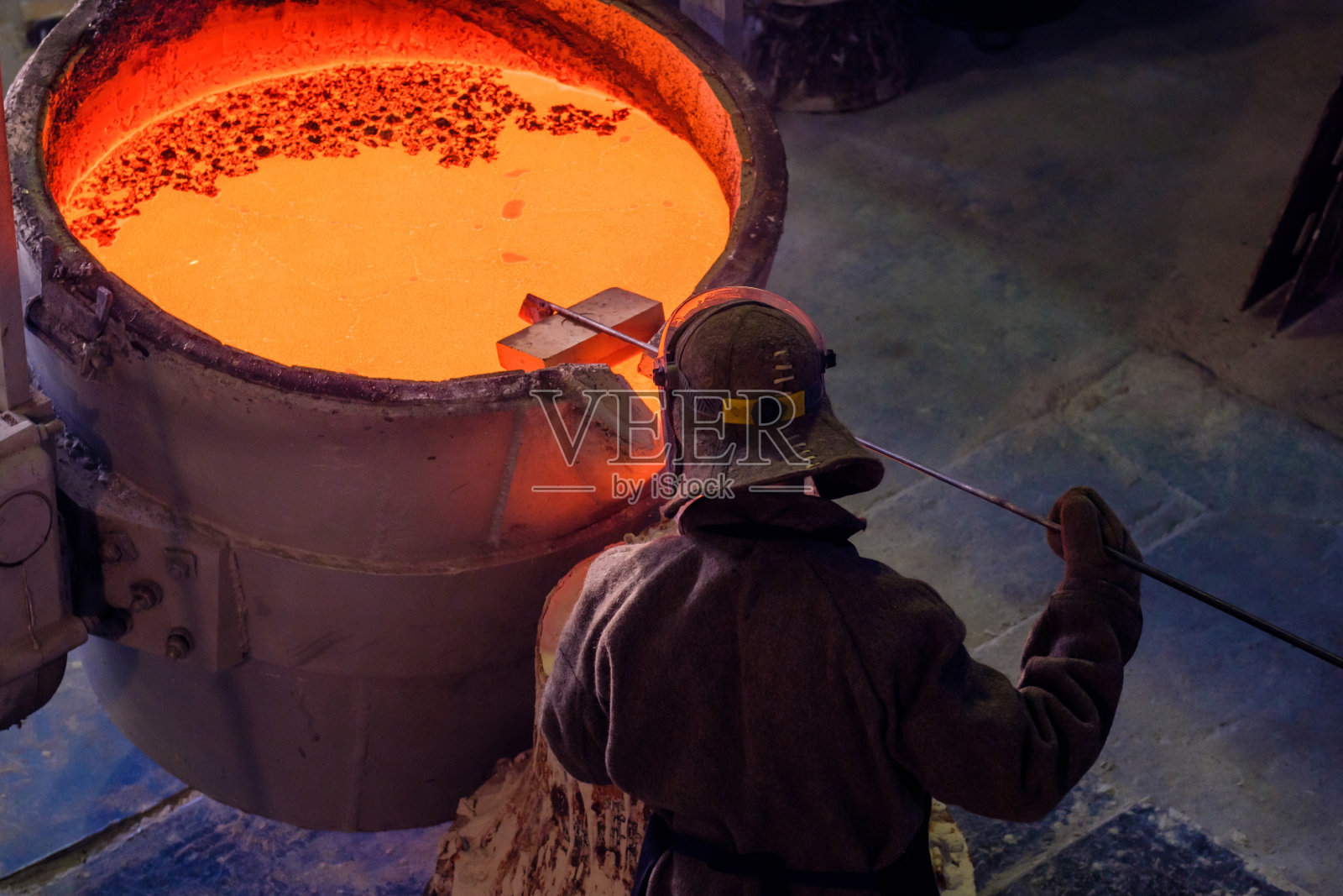 俯视图的大桶与红色熔融金属和工人检查一致性状态前浇注照片摄影图片