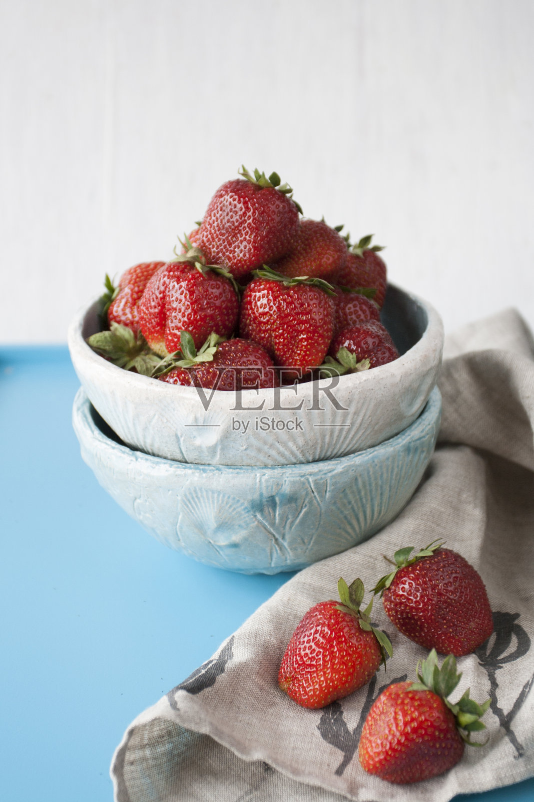 蓝色的雏菊，红色多汁的草莓，蓝色的木制背景照片摄影图片